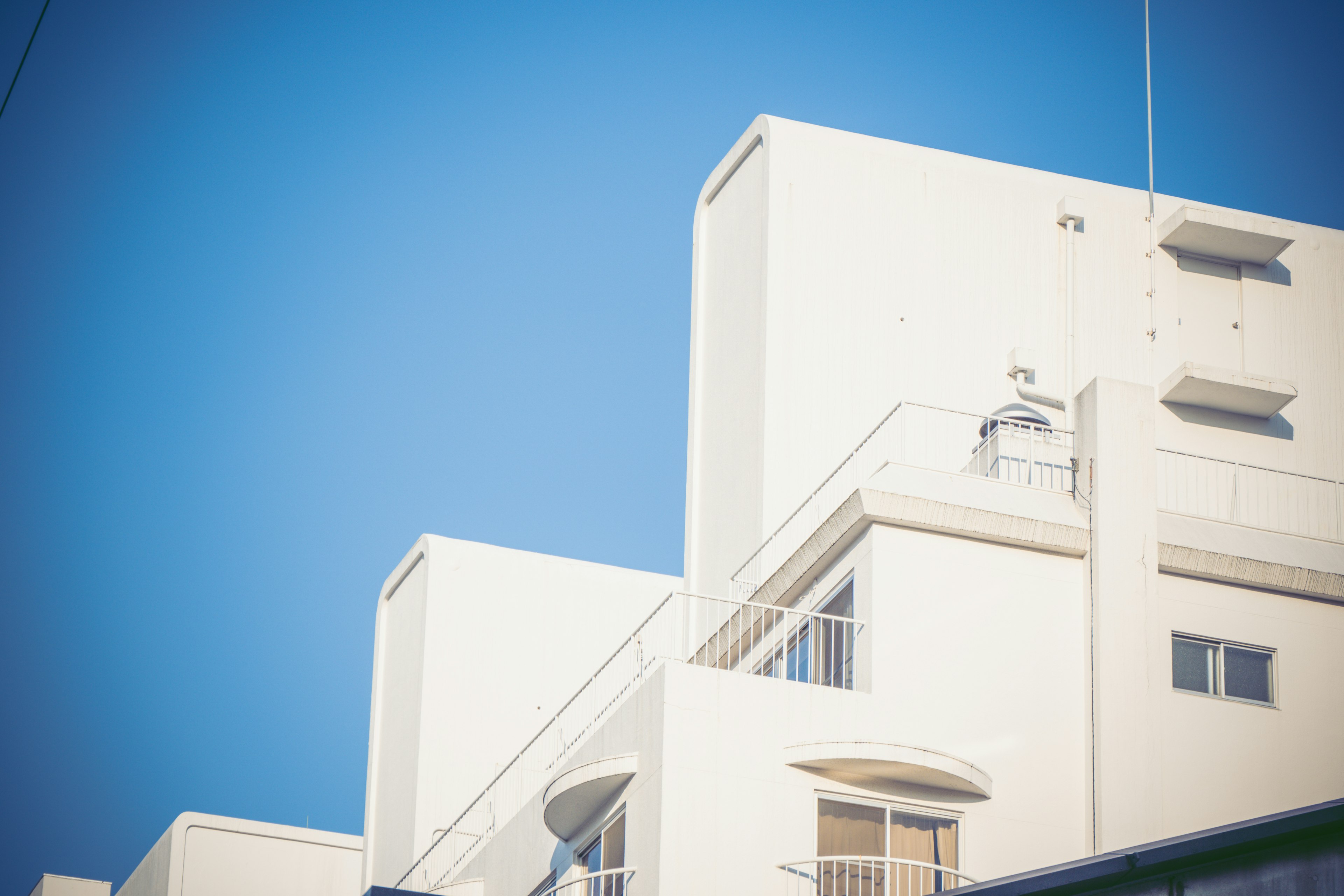 Part of a modern white building under a blue sky