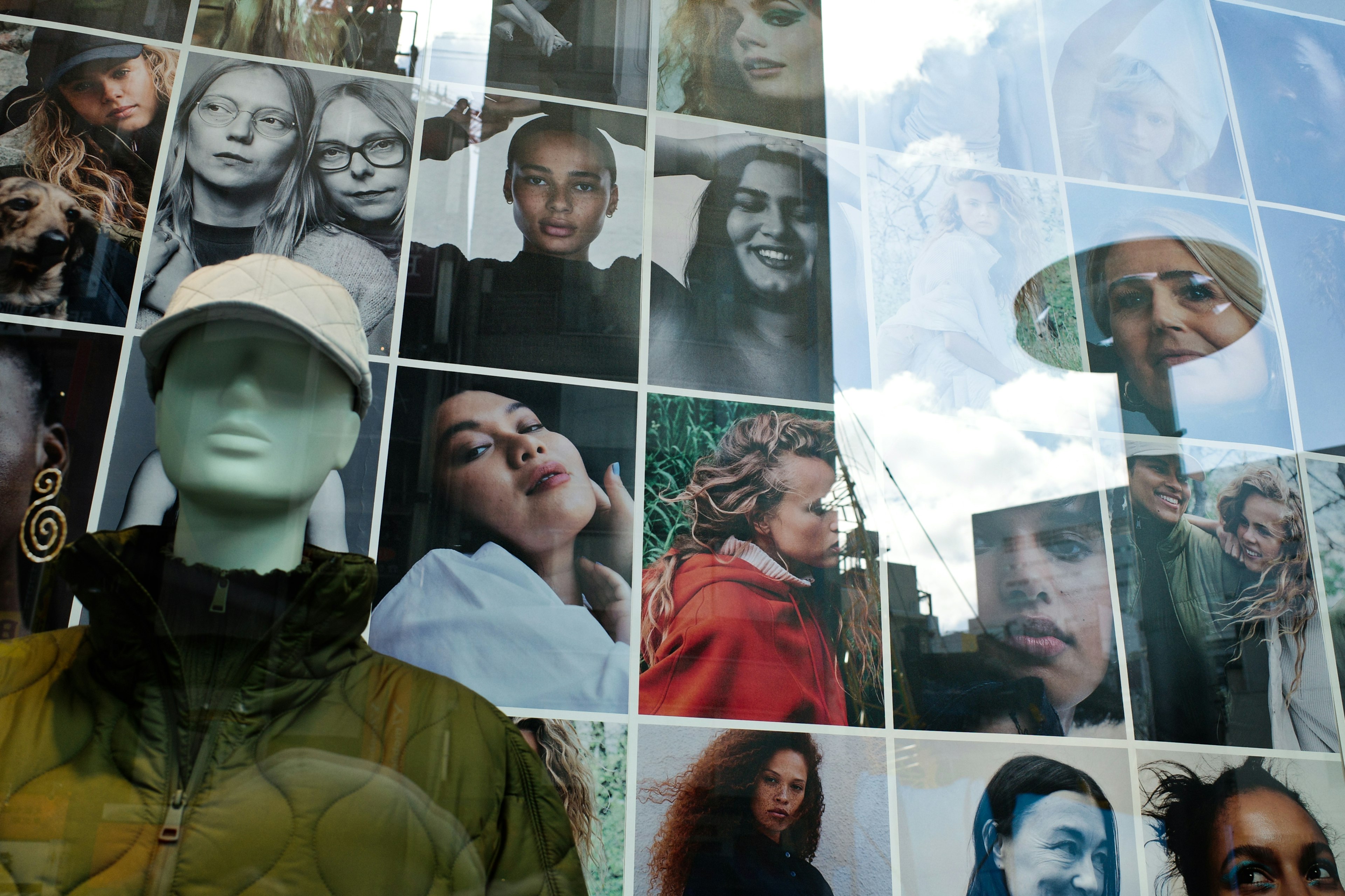 Vitrine avec des portraits de visages divers et un mannequin vert