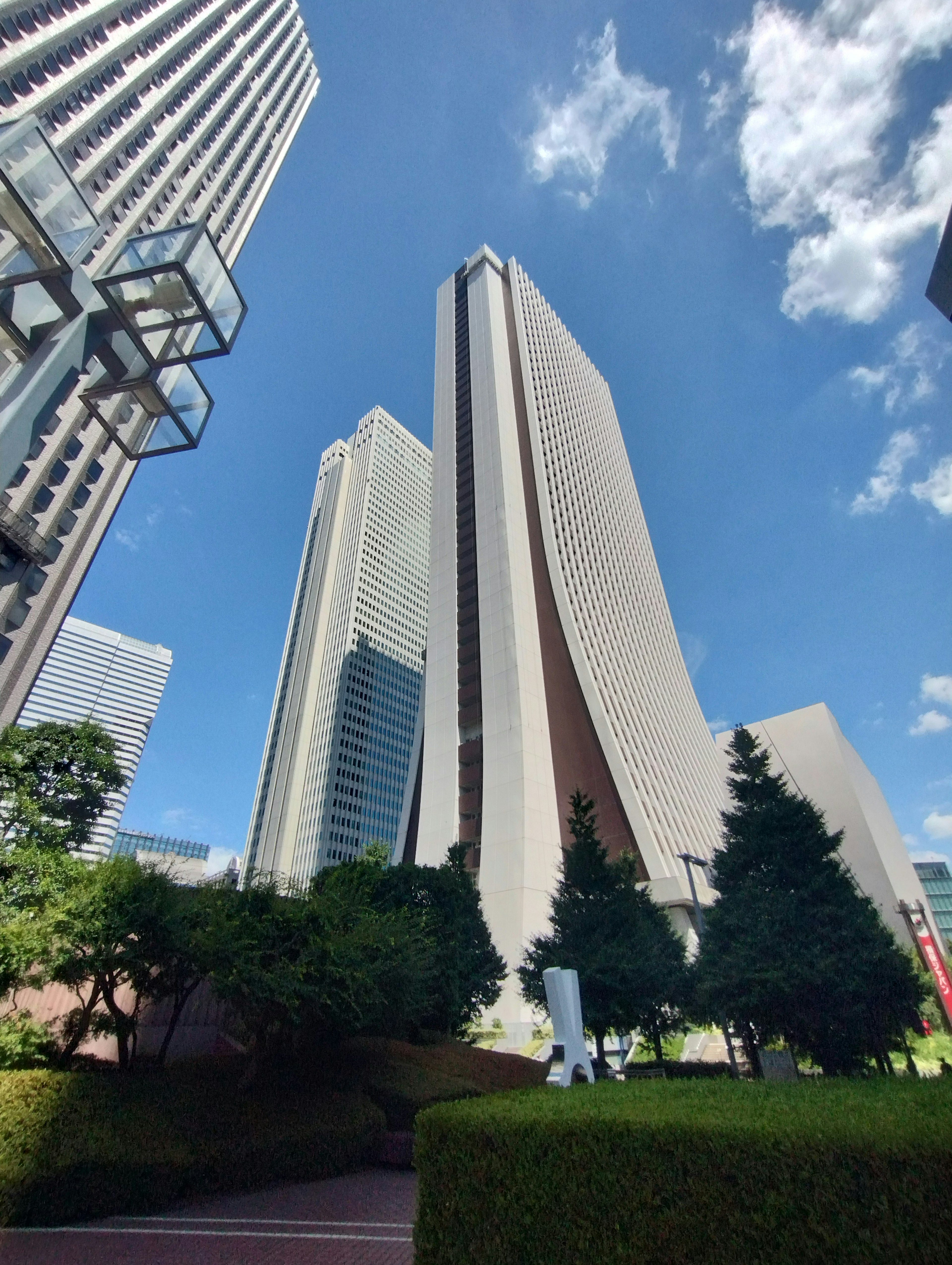 Stunning view of skyscrapers against a blue sky with clouds and lush greenery