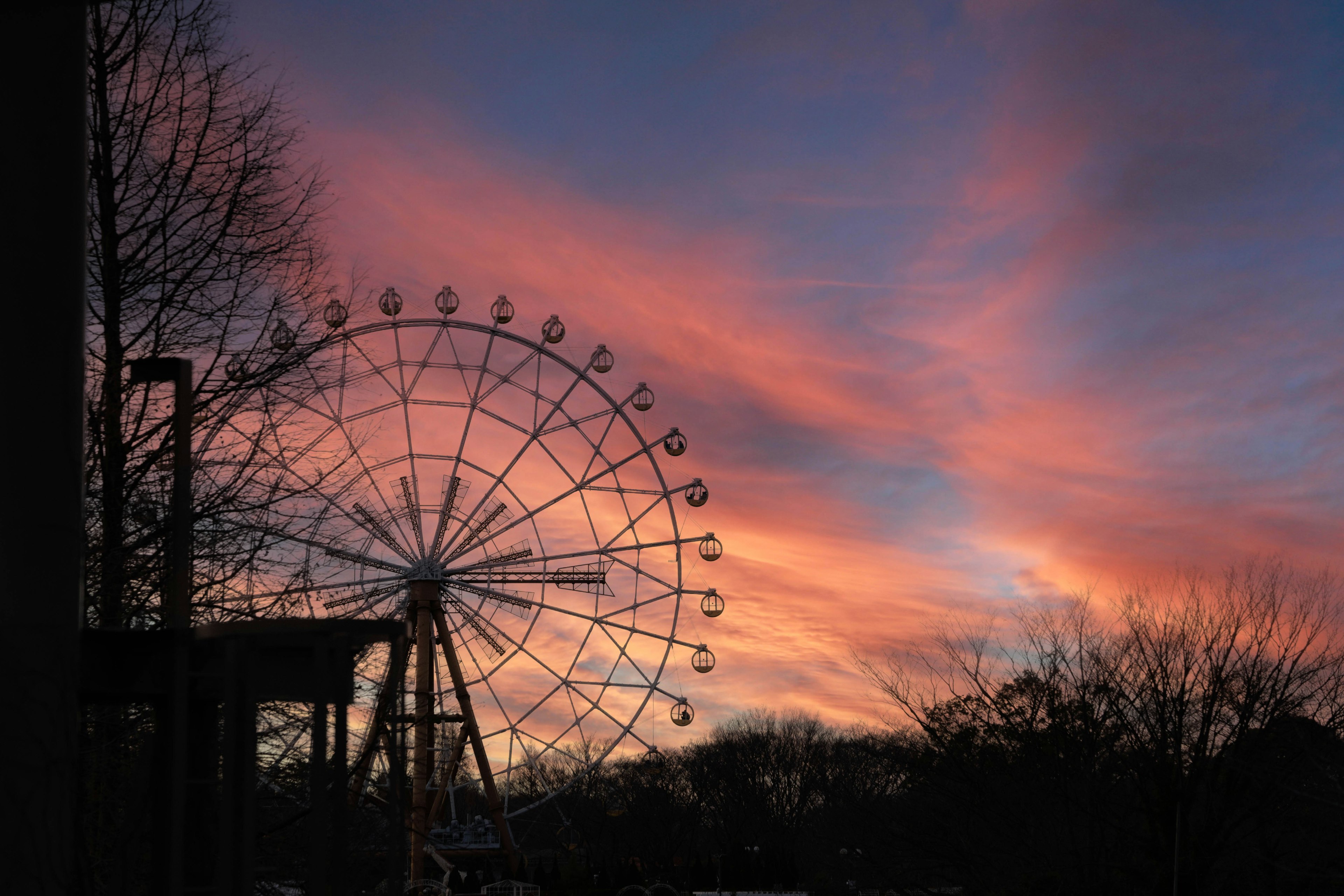 夕焼けの空の中に大きな観覧車が silhouetted されている風景