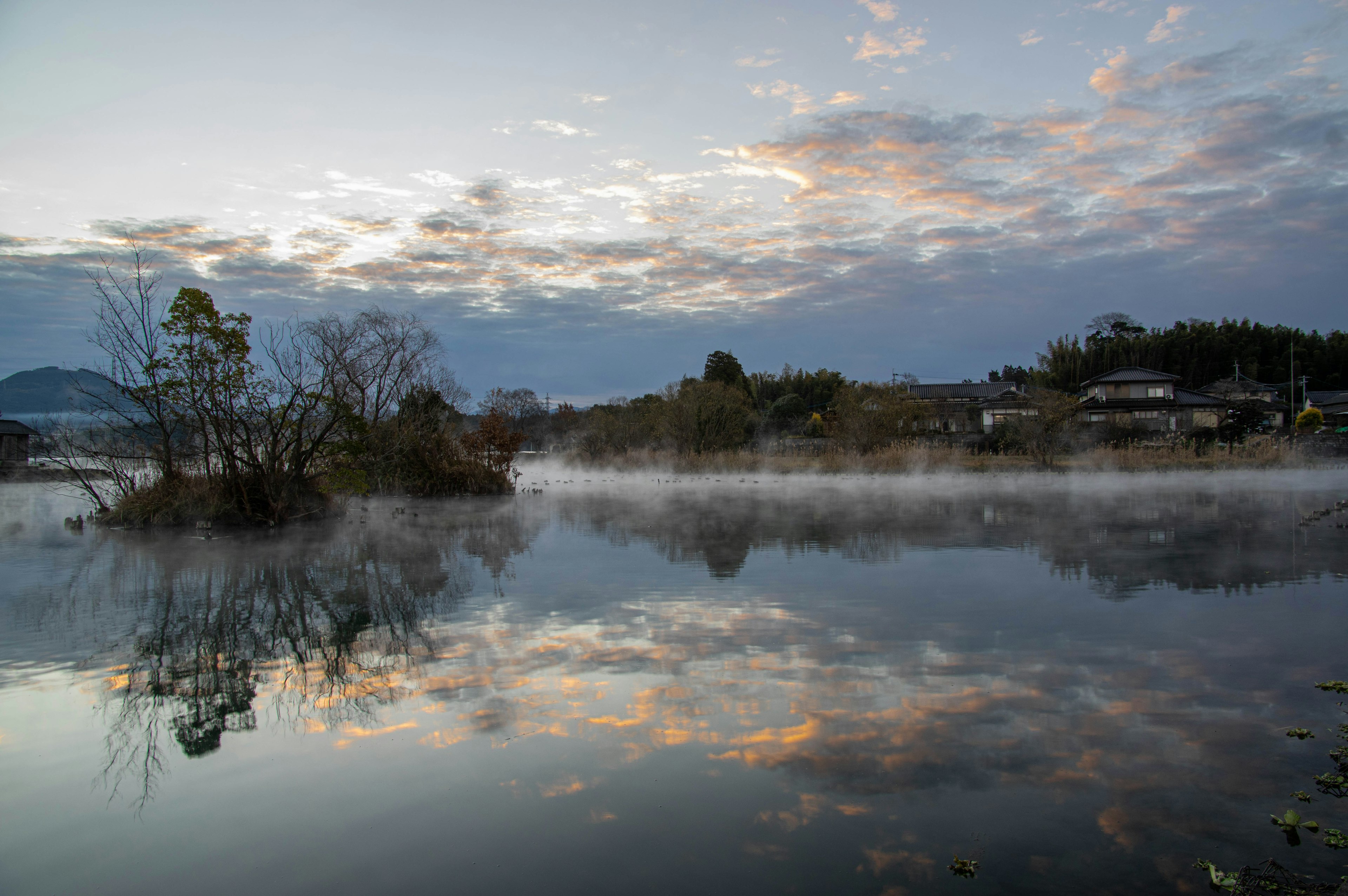 Ruhiger See mit Nebel und Wolkenreflexionen