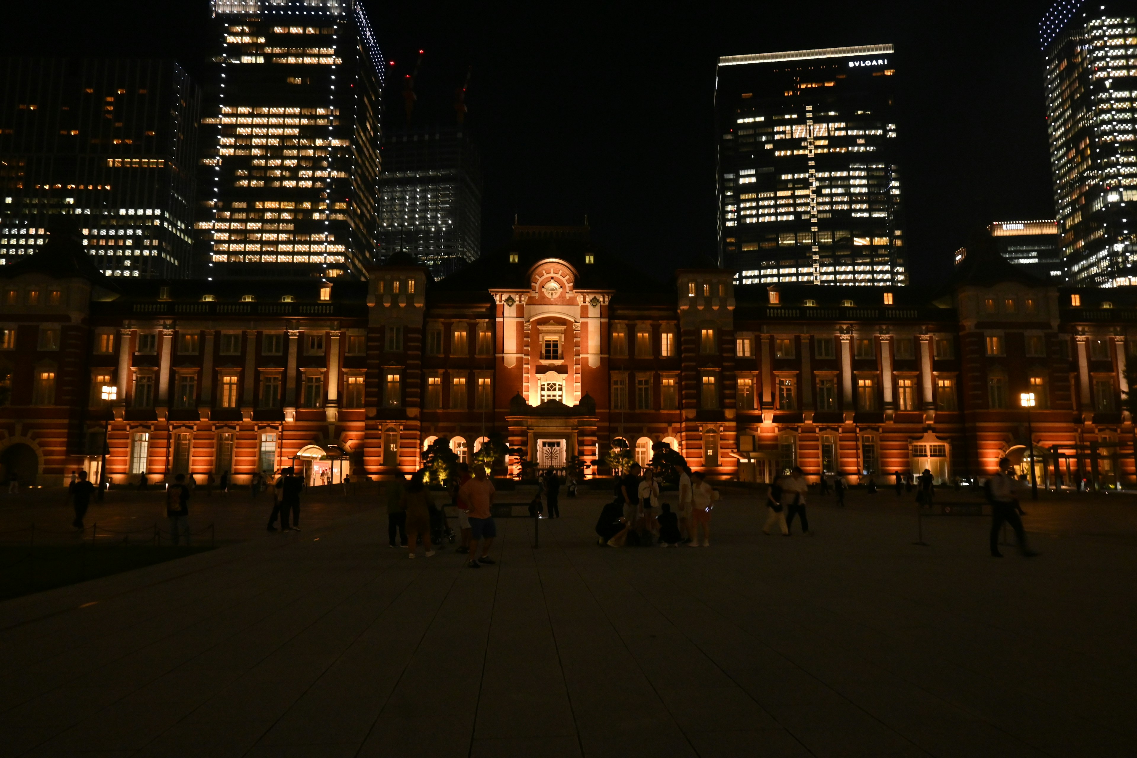 東京駅の夜景と周囲の高層ビル群と人々