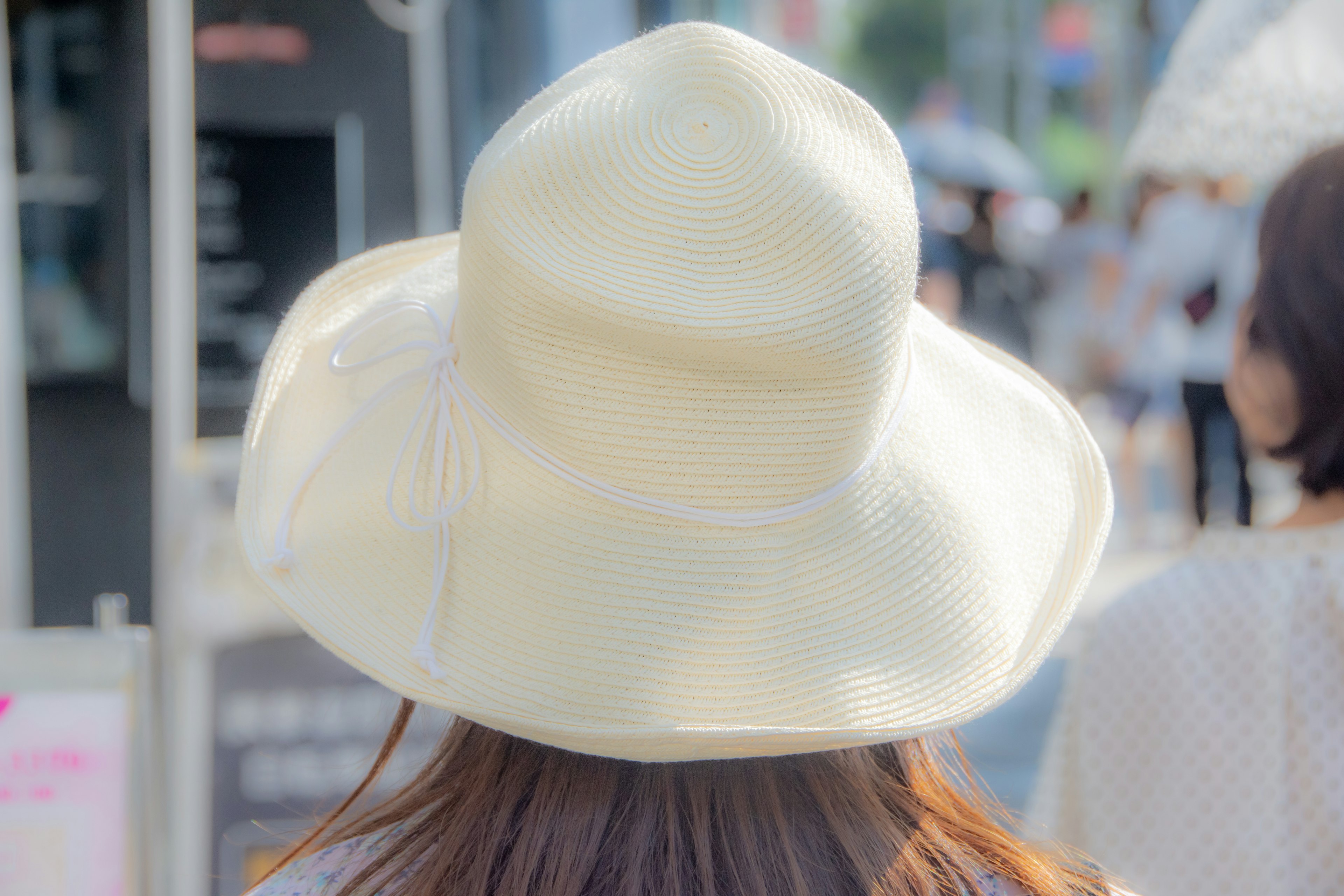 Photo d'une femme portant un chapeau blanc de dos