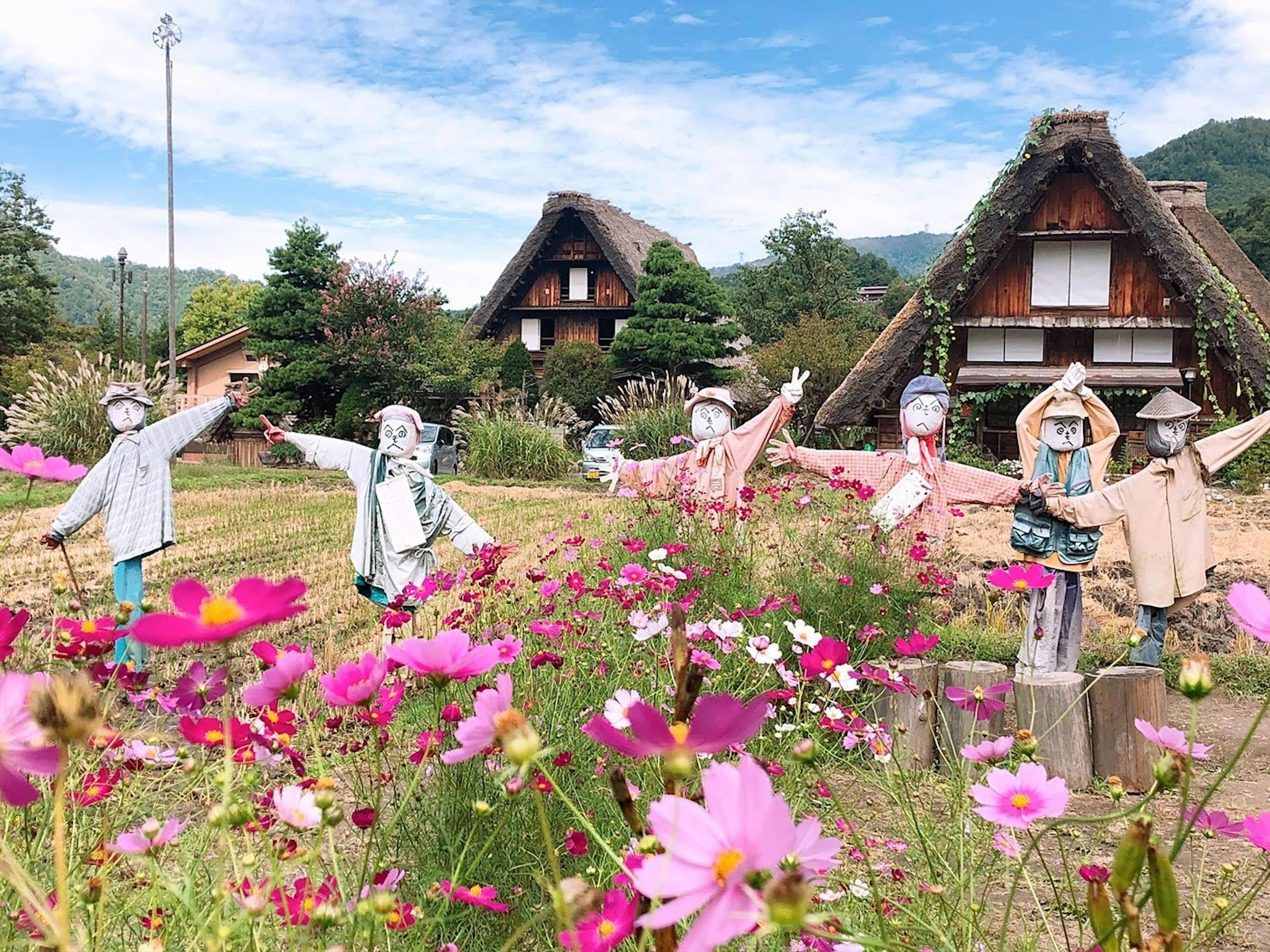 Malersicher Blick auf traditionelle Strohhäuser mit Figuren, die zwischen bunten Blumen posieren