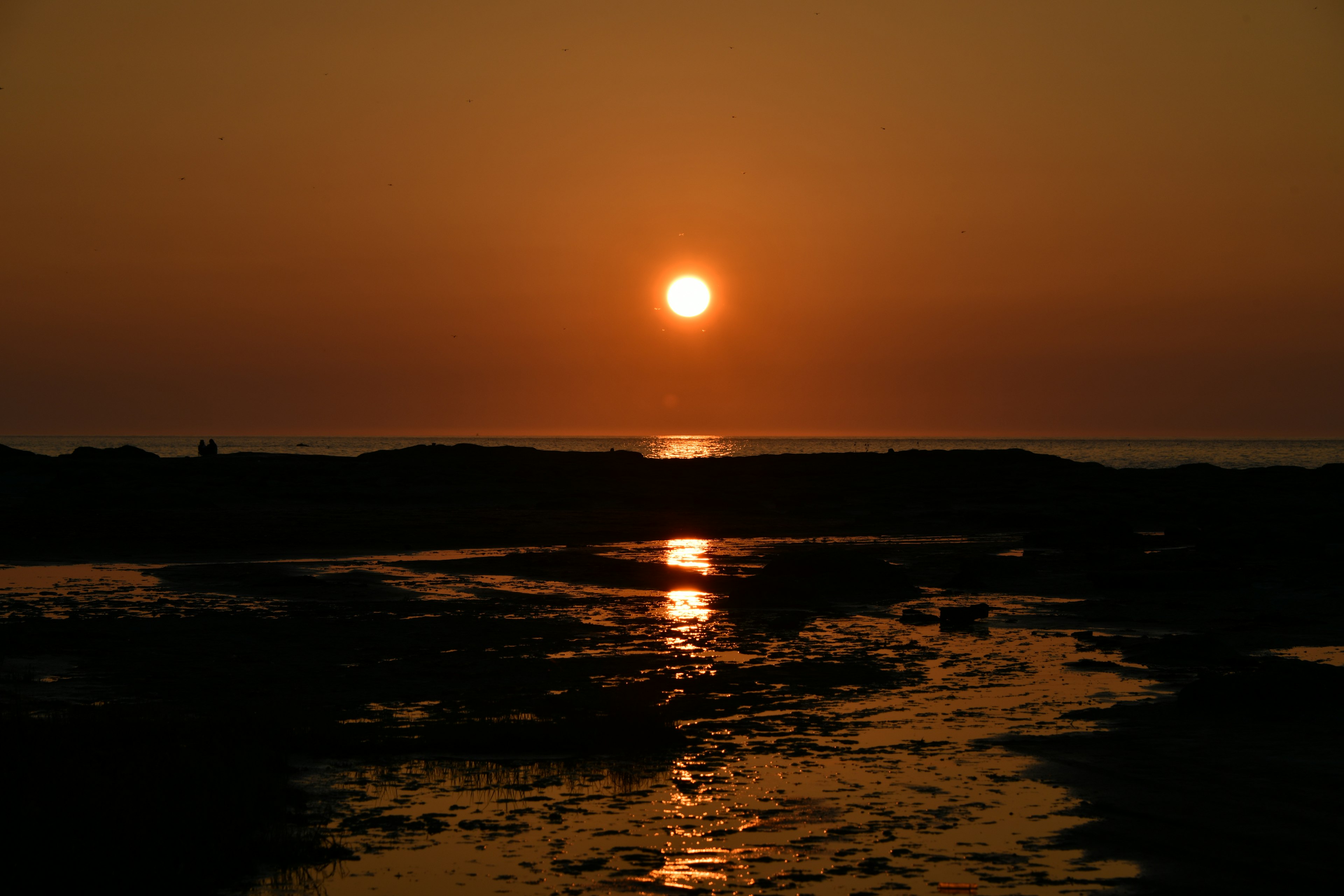 Sonnenuntergang über dem Ozean mit Spiegelungen auf ruhigem Wasser