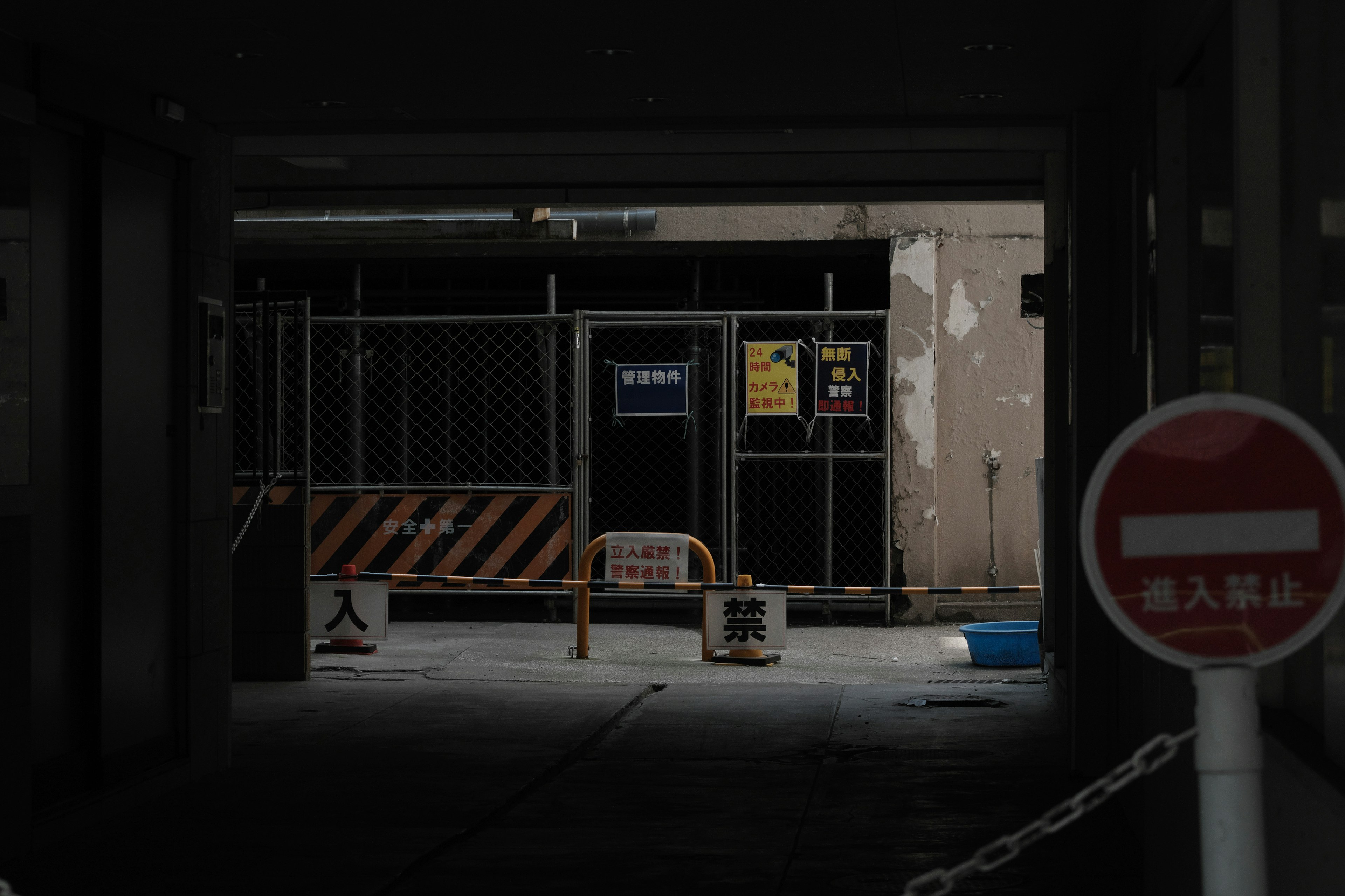 Couloir sombre menant à une entrée fermée avec des barrières de construction