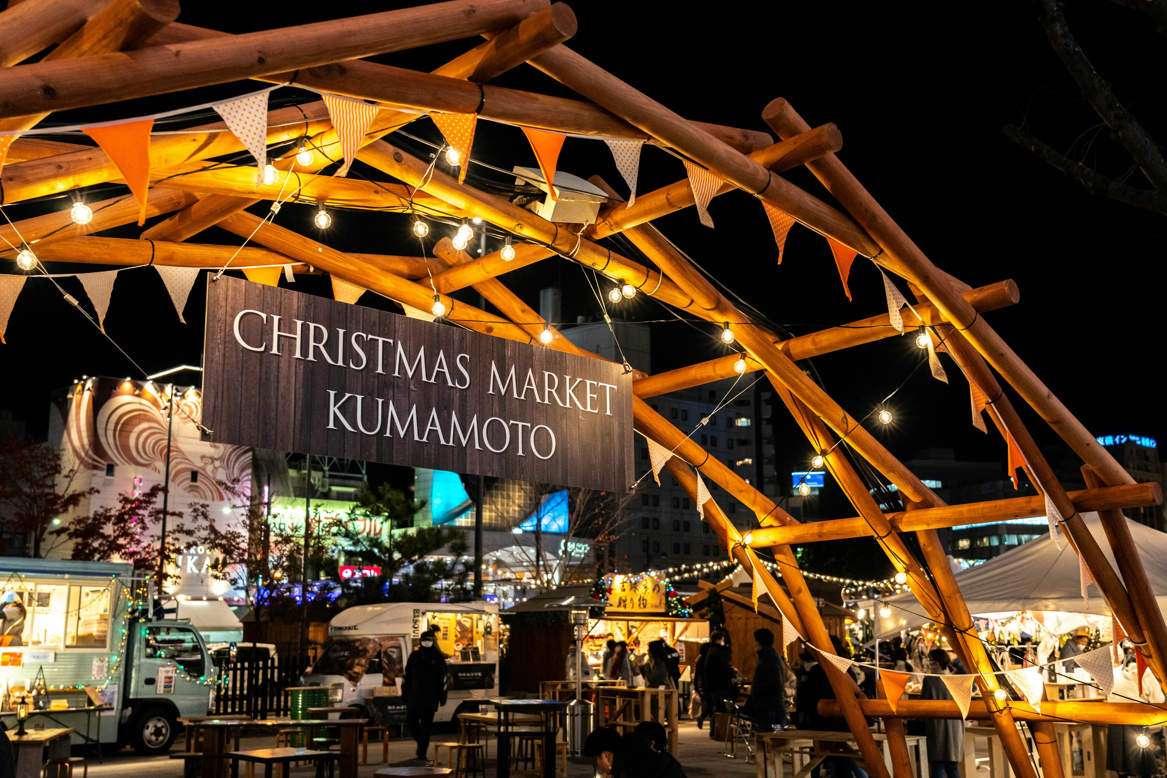 Vue nocturne du marché de Noël Kumamoto avec des tentes illuminées et des décorations festives