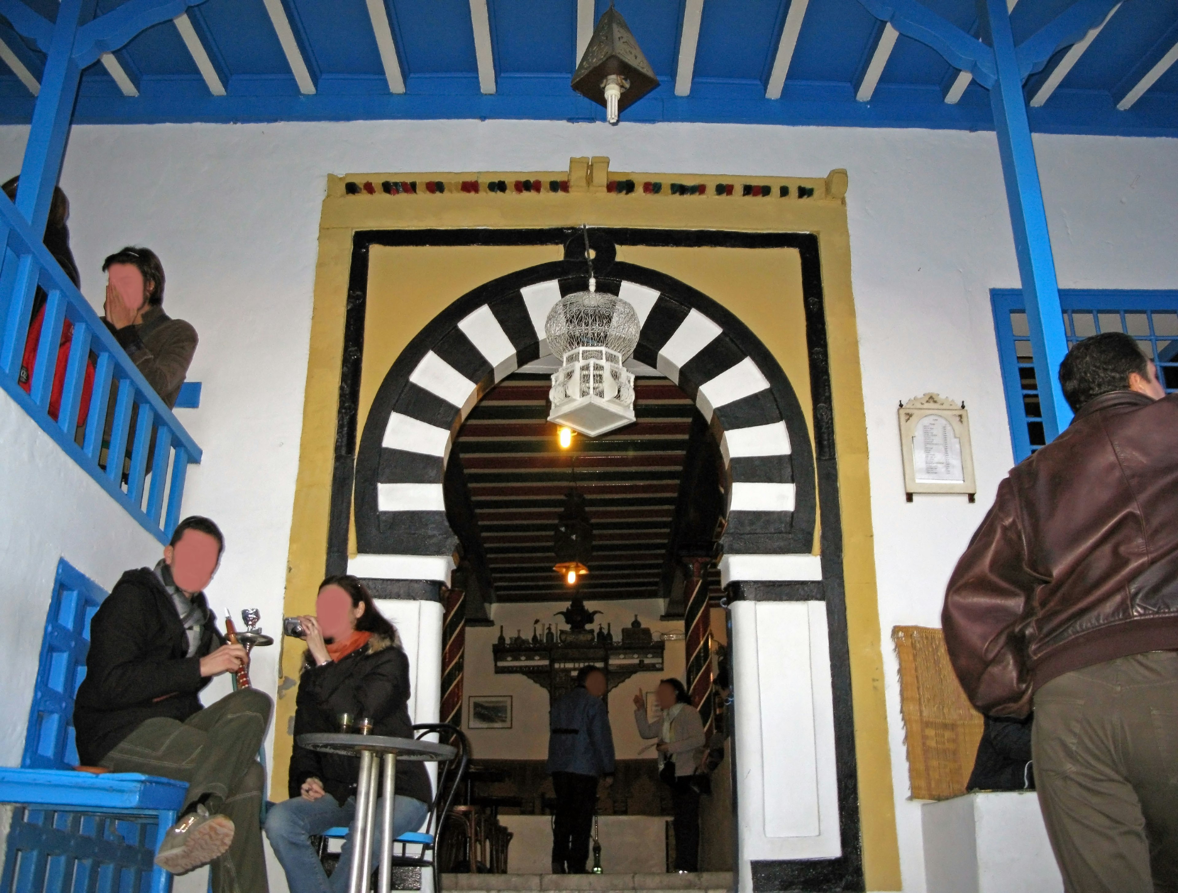 Interior of a café featuring a blue balcony and striped arch