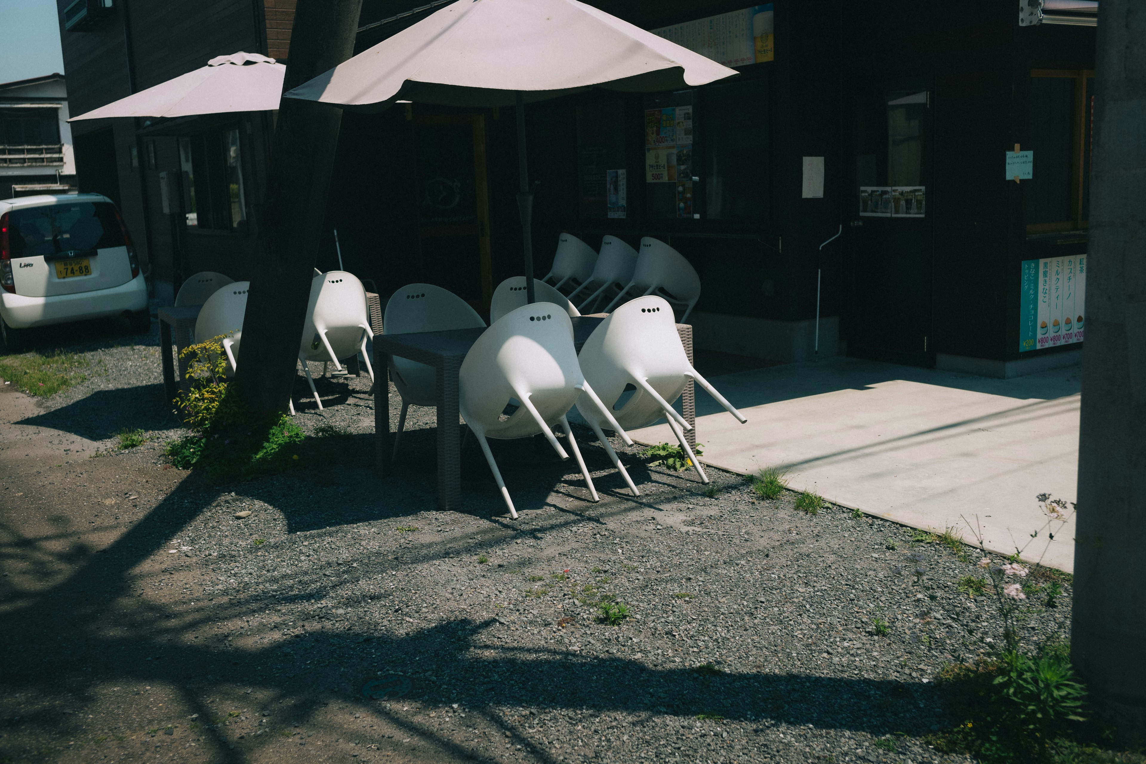 Outdoor terrace with white chairs and shaded umbrellas