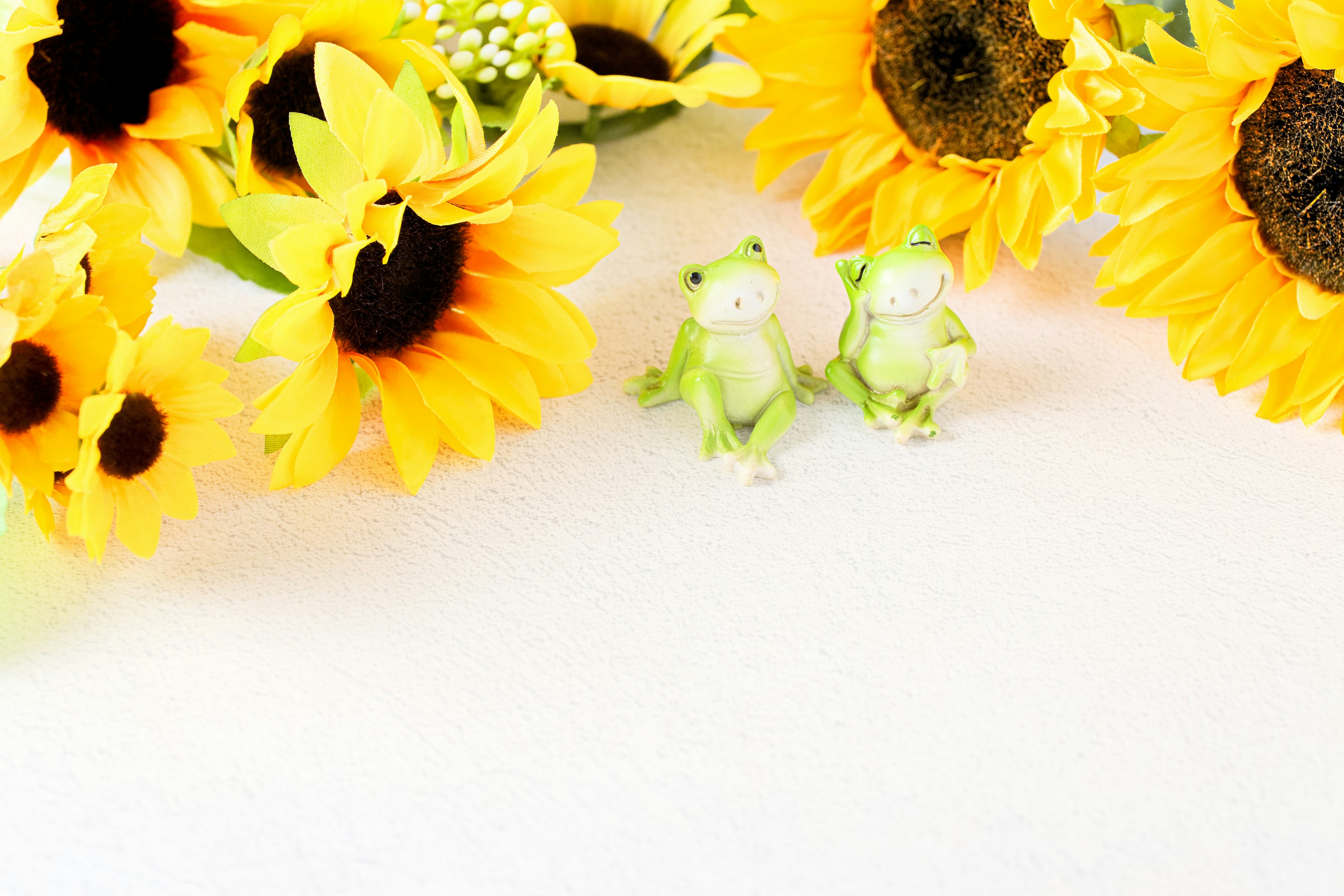 Helle Abbildung mit Sonnenblumen und Froschfiguren