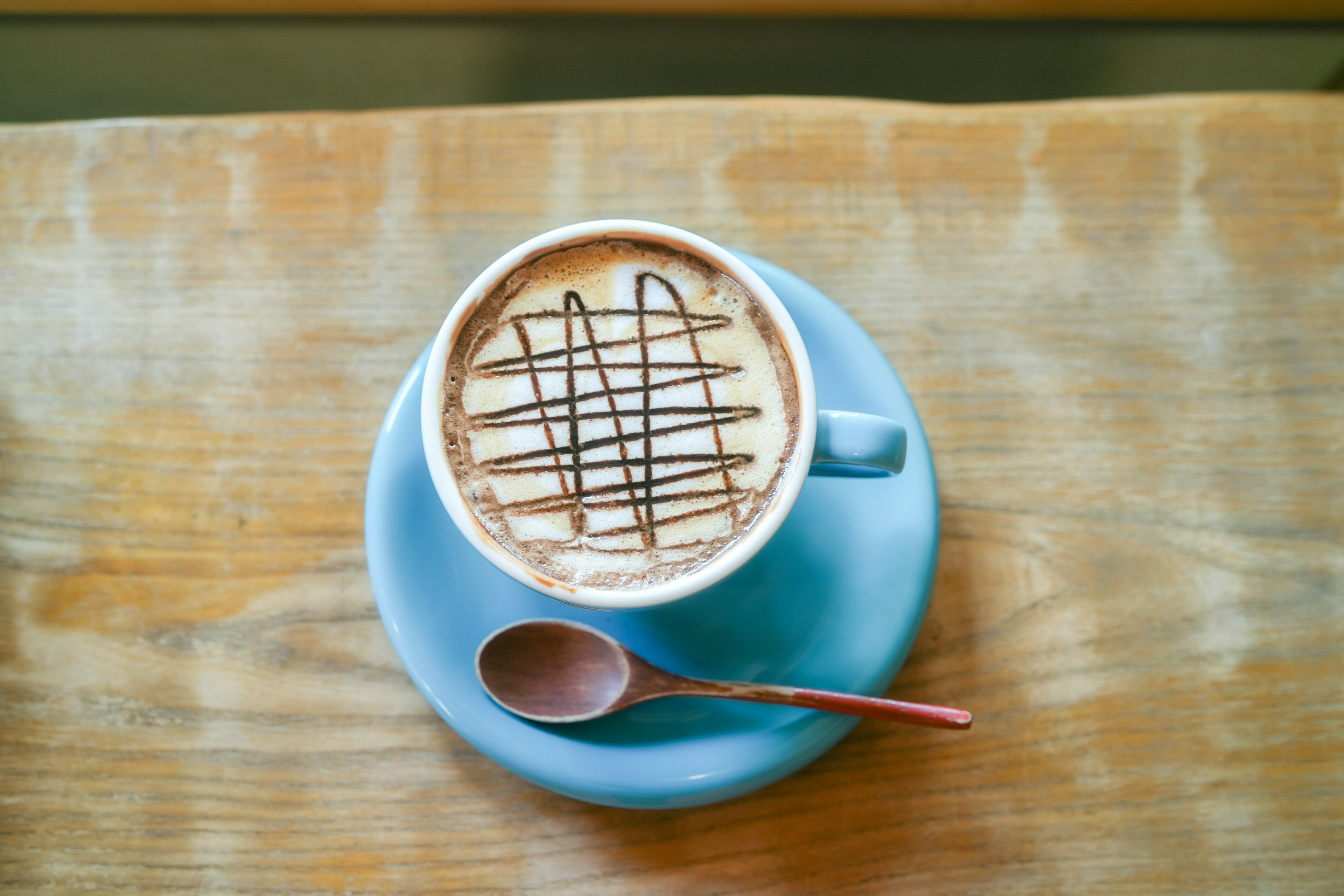 Kopi dalam cangkir biru dengan desain coklat di atasnya