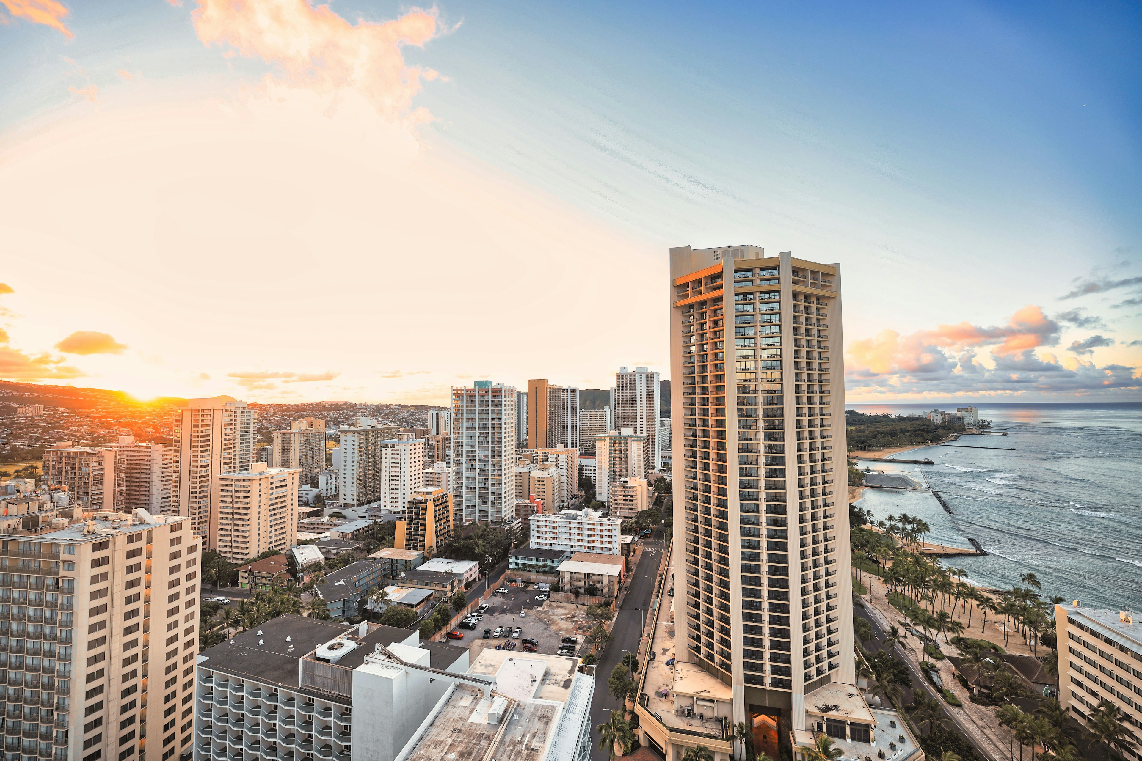 Sunset view over a city skyline with high-rise buildings and ocean