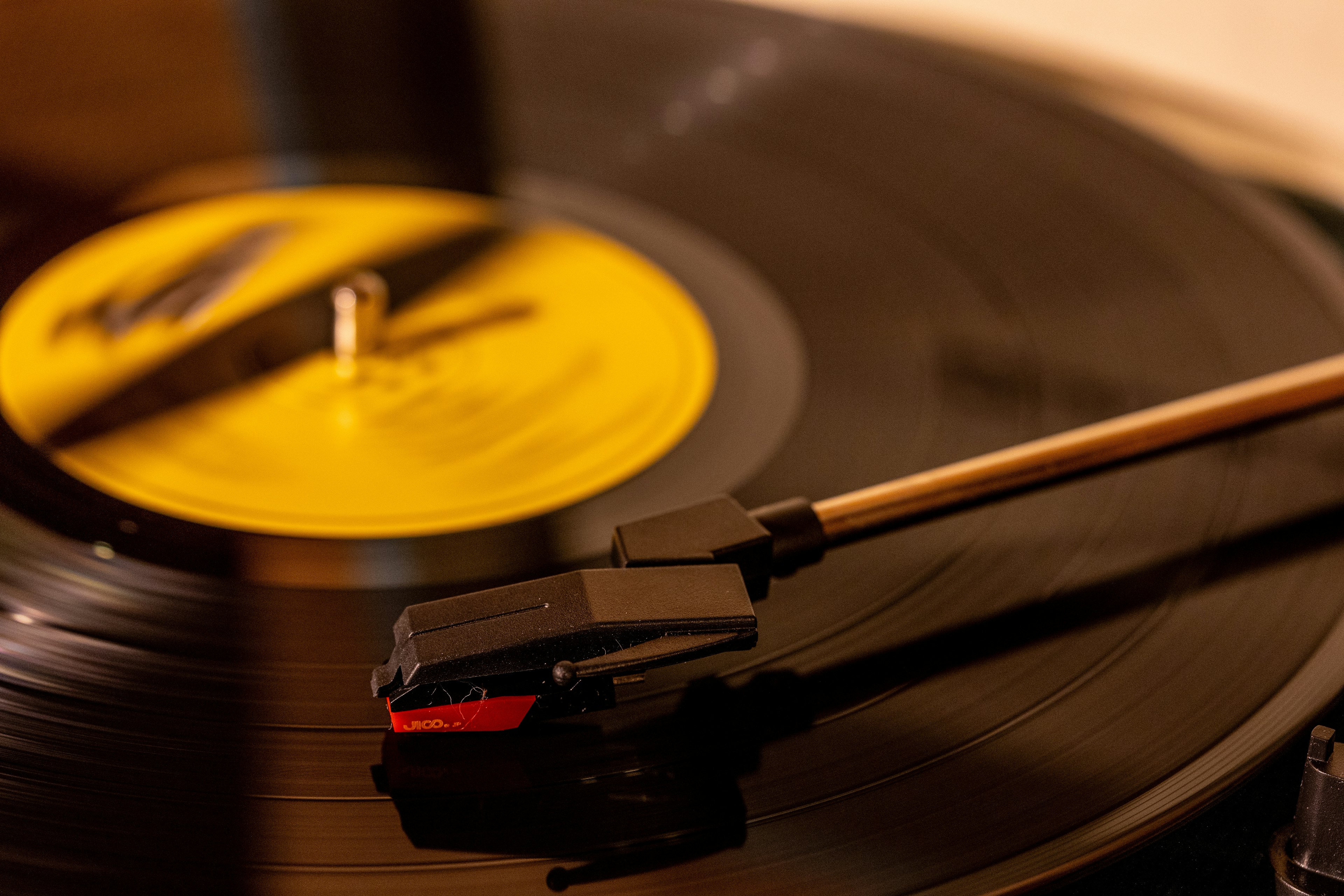 Primo piano di un disco in vinile nero con un'etichetta gialla su un giradischi