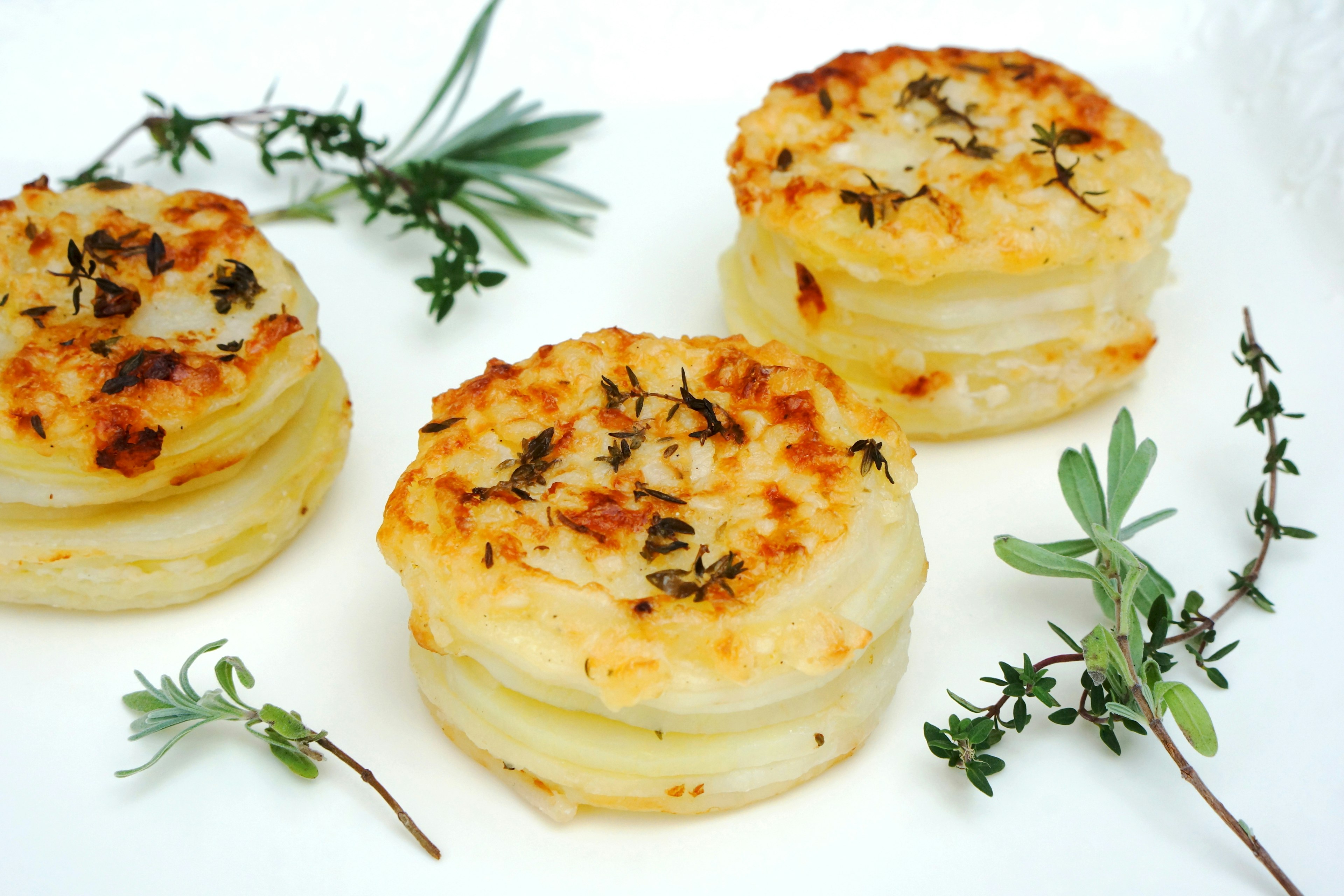 Rondas de gratén de papa al horno decoradas con hierbas frescas