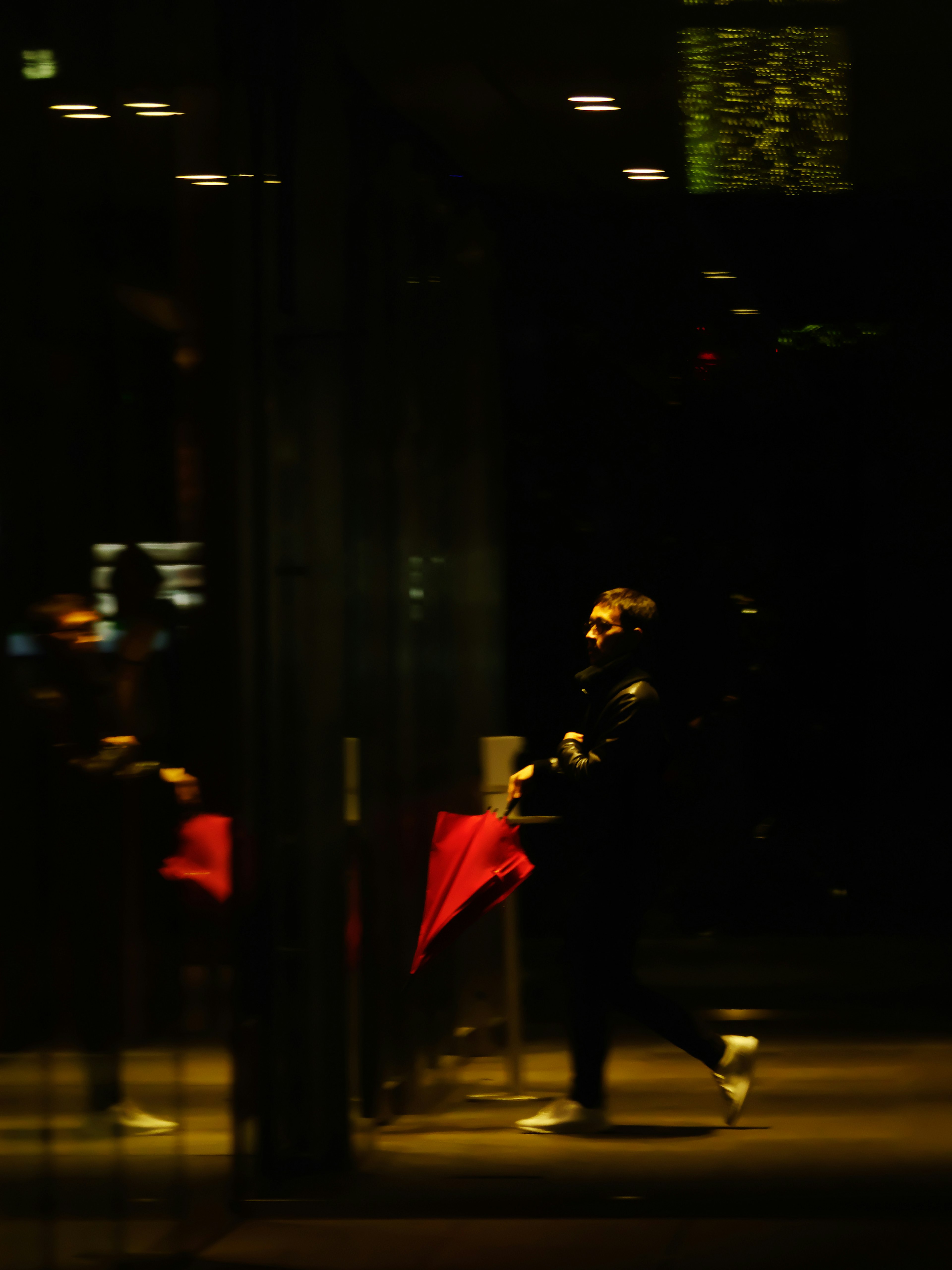 Une personne passant devant une table avec une nappe rouge dans un environnement sombre