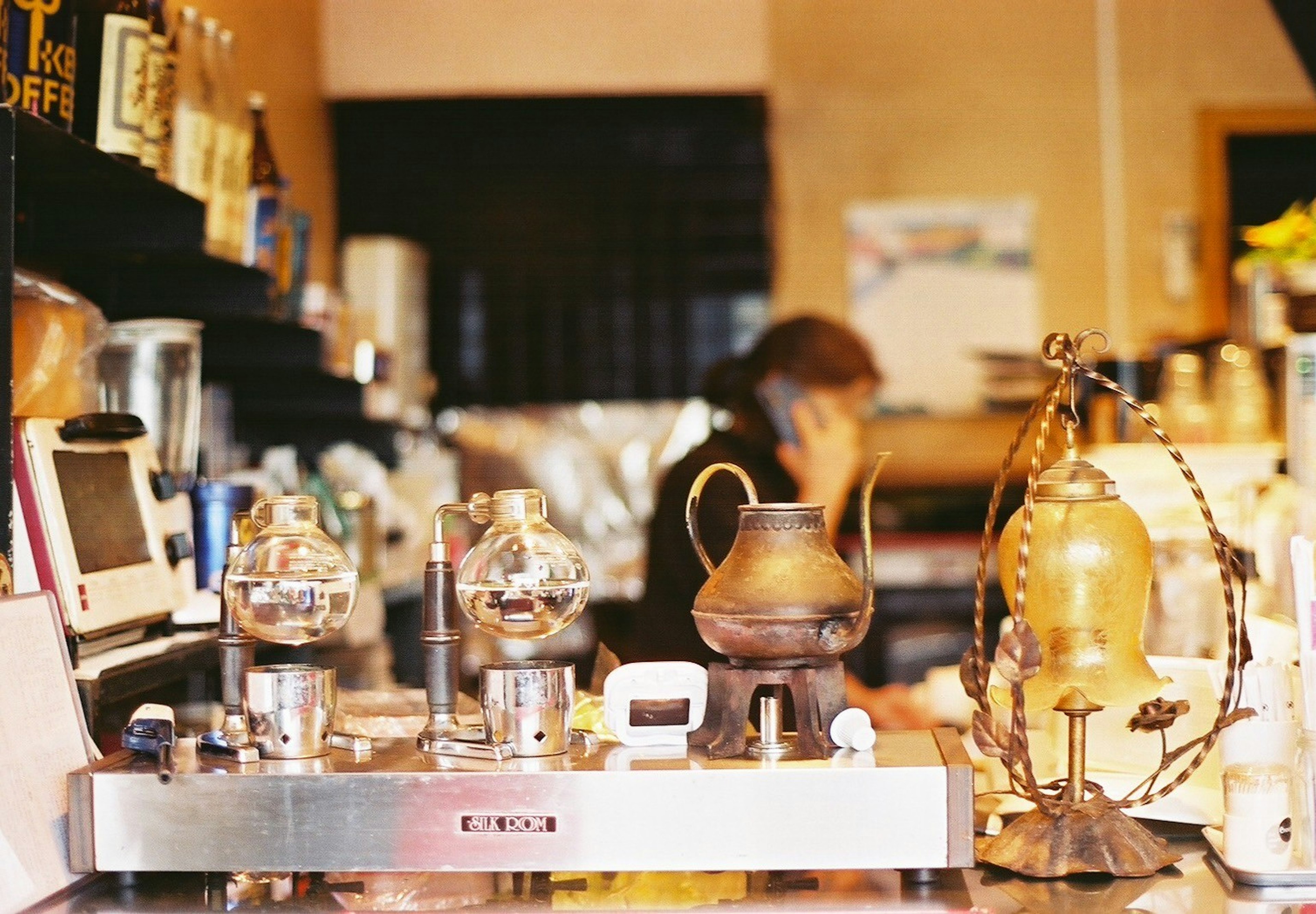 Interior de una cafetería con equipo de café y un empleado