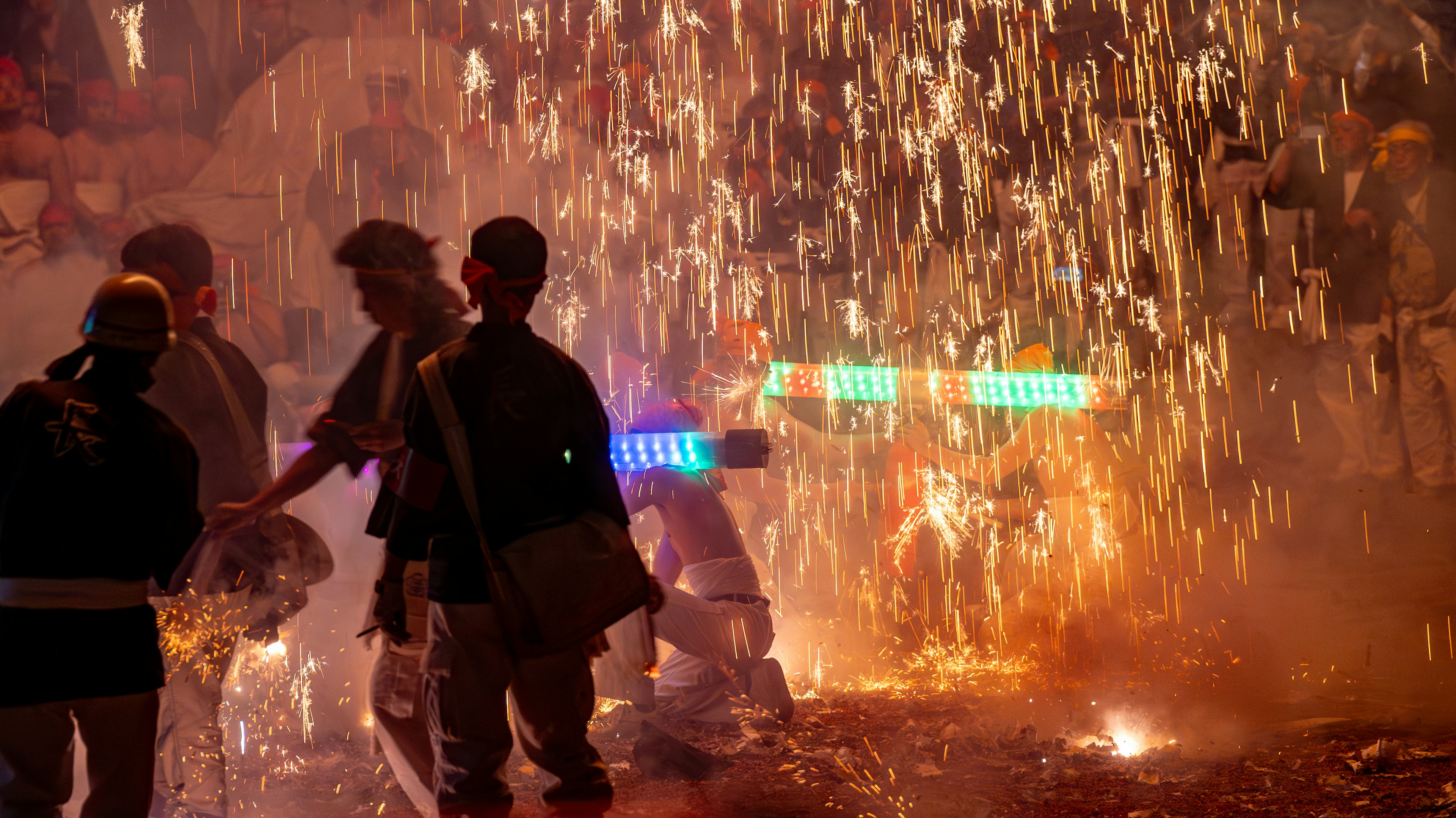 Festival scene with people surrounded by sparks and colorful lights