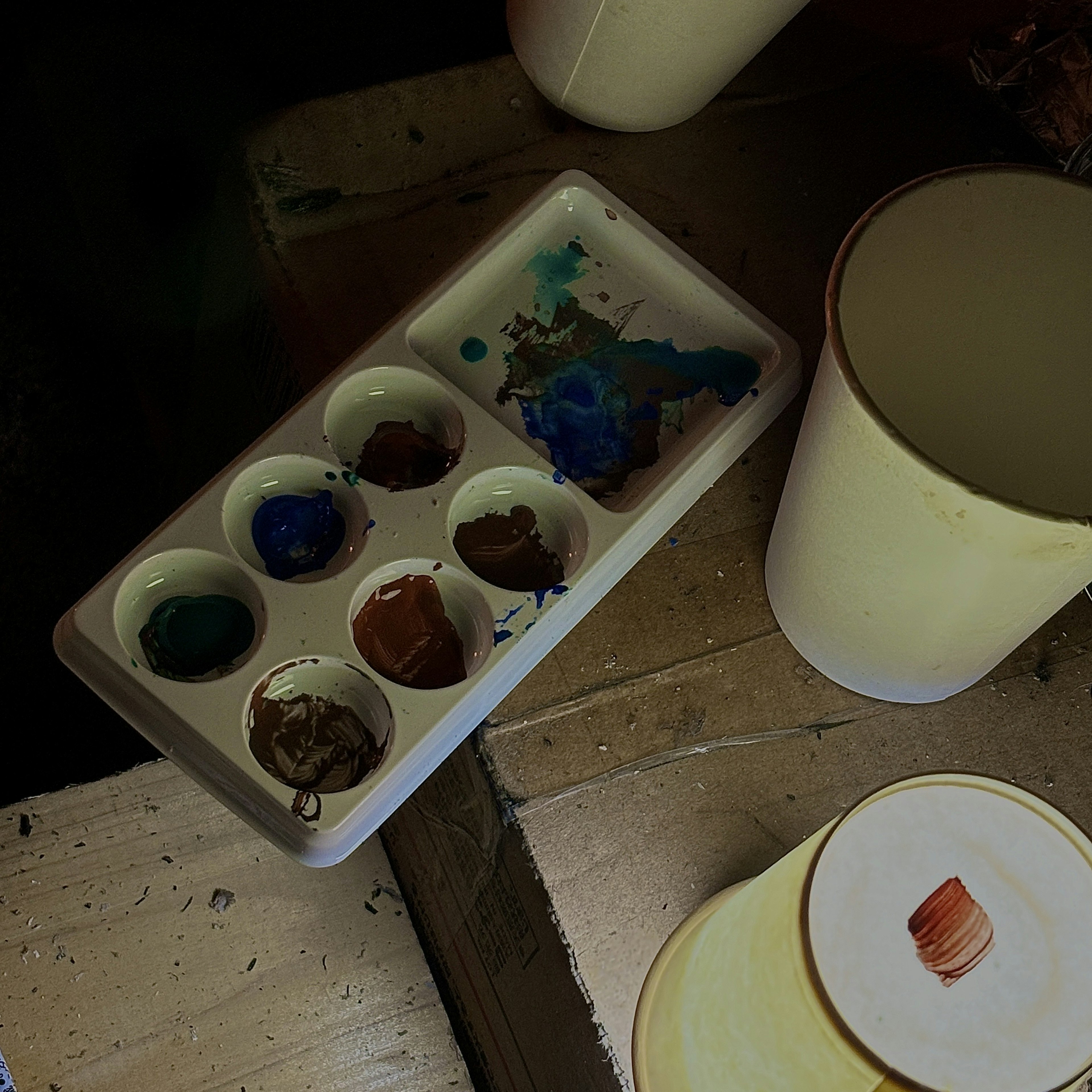 Tazas amarillas y una paleta con varios colores de pintura