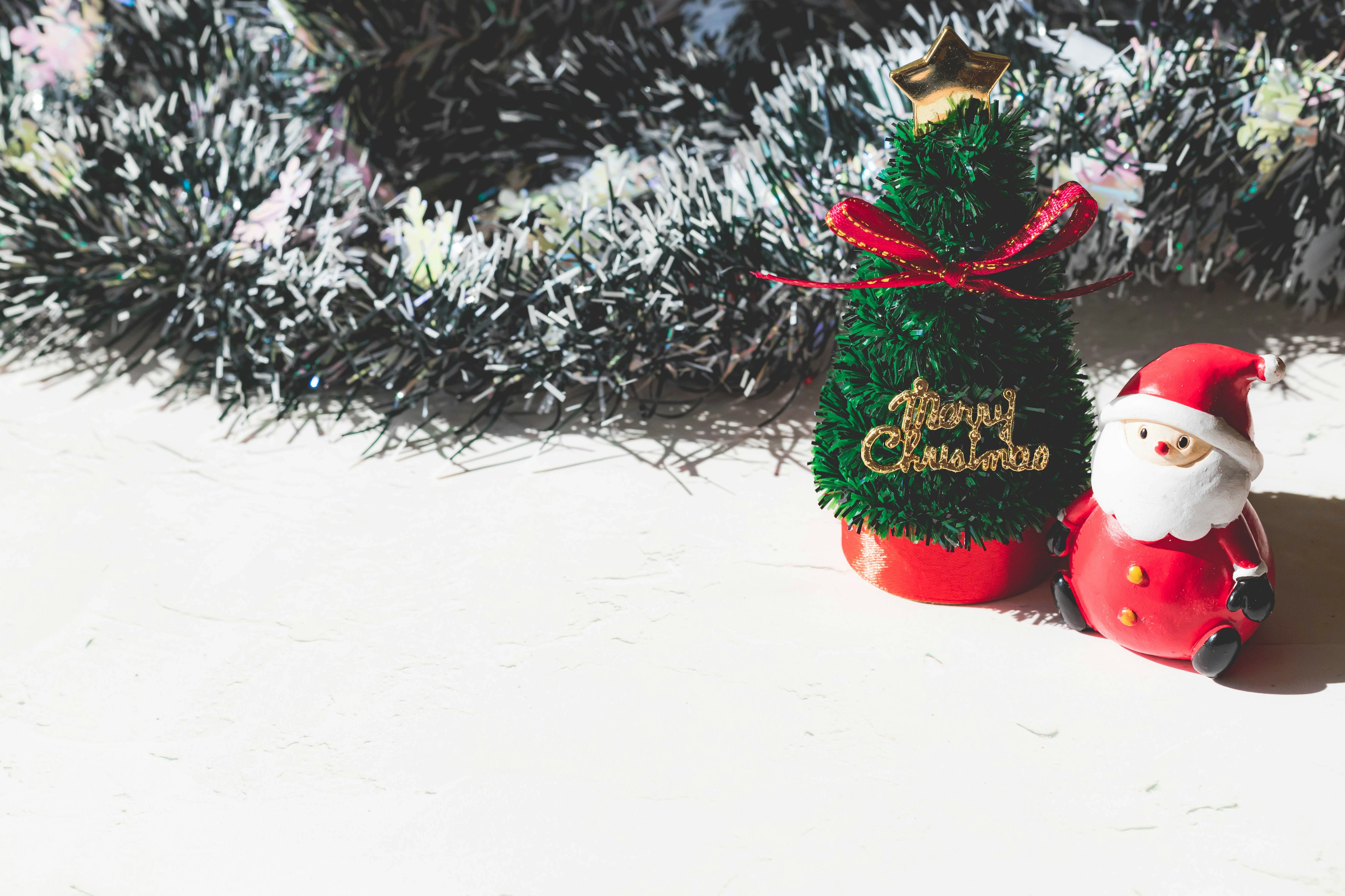 Ein kleiner Weihnachtsbaum und eine Weihnachtsmannfigur auf einem weißen Tisch