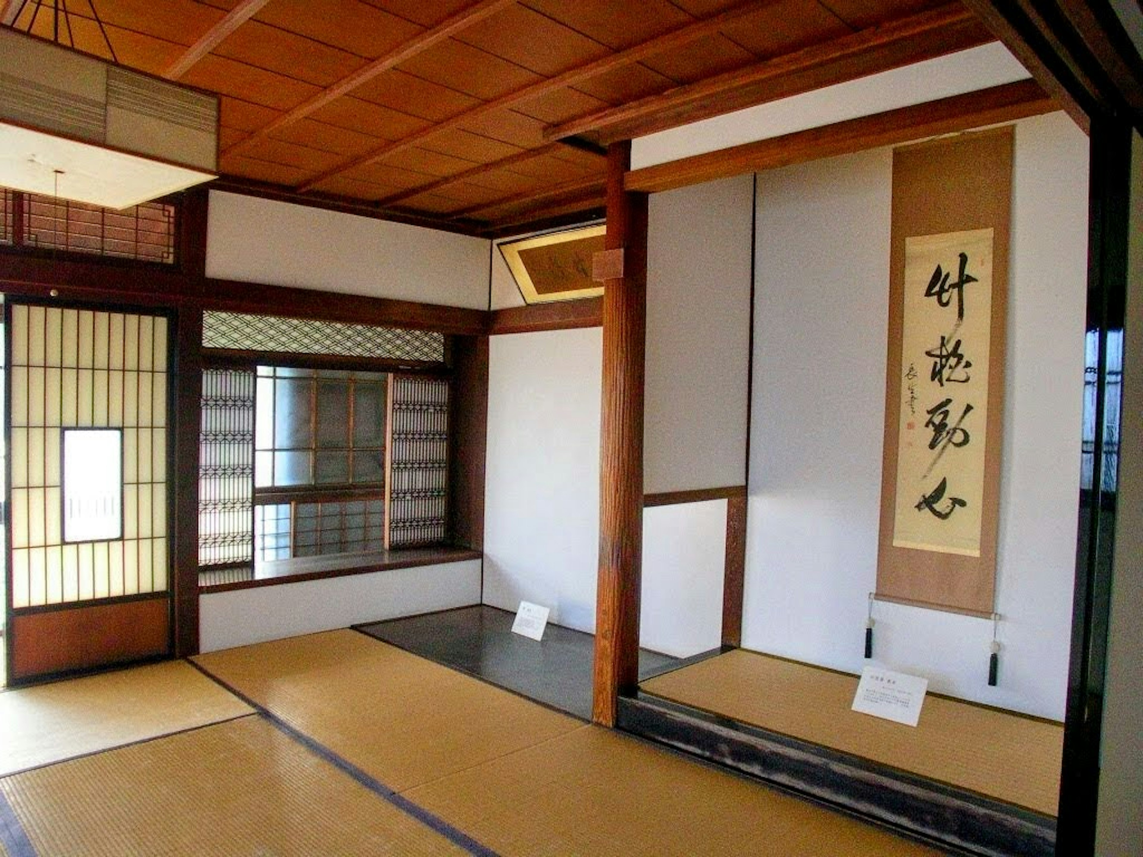 Traditionelles japanisches Zimmerinterieur mit Shoji-Schirmen, hängendem Rollbild und Tatami-Boden