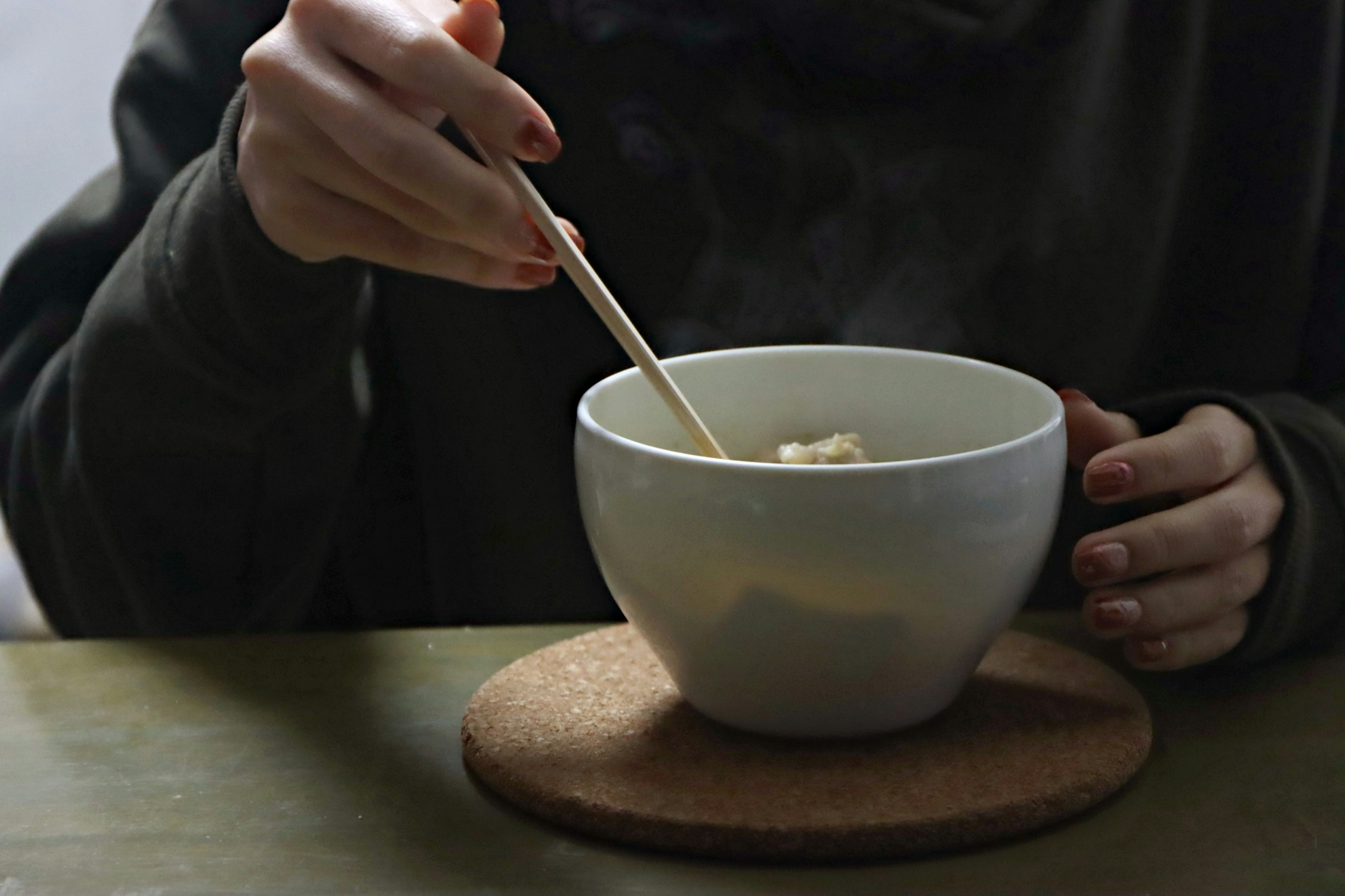 スープを食べる手と白いボウルの写真