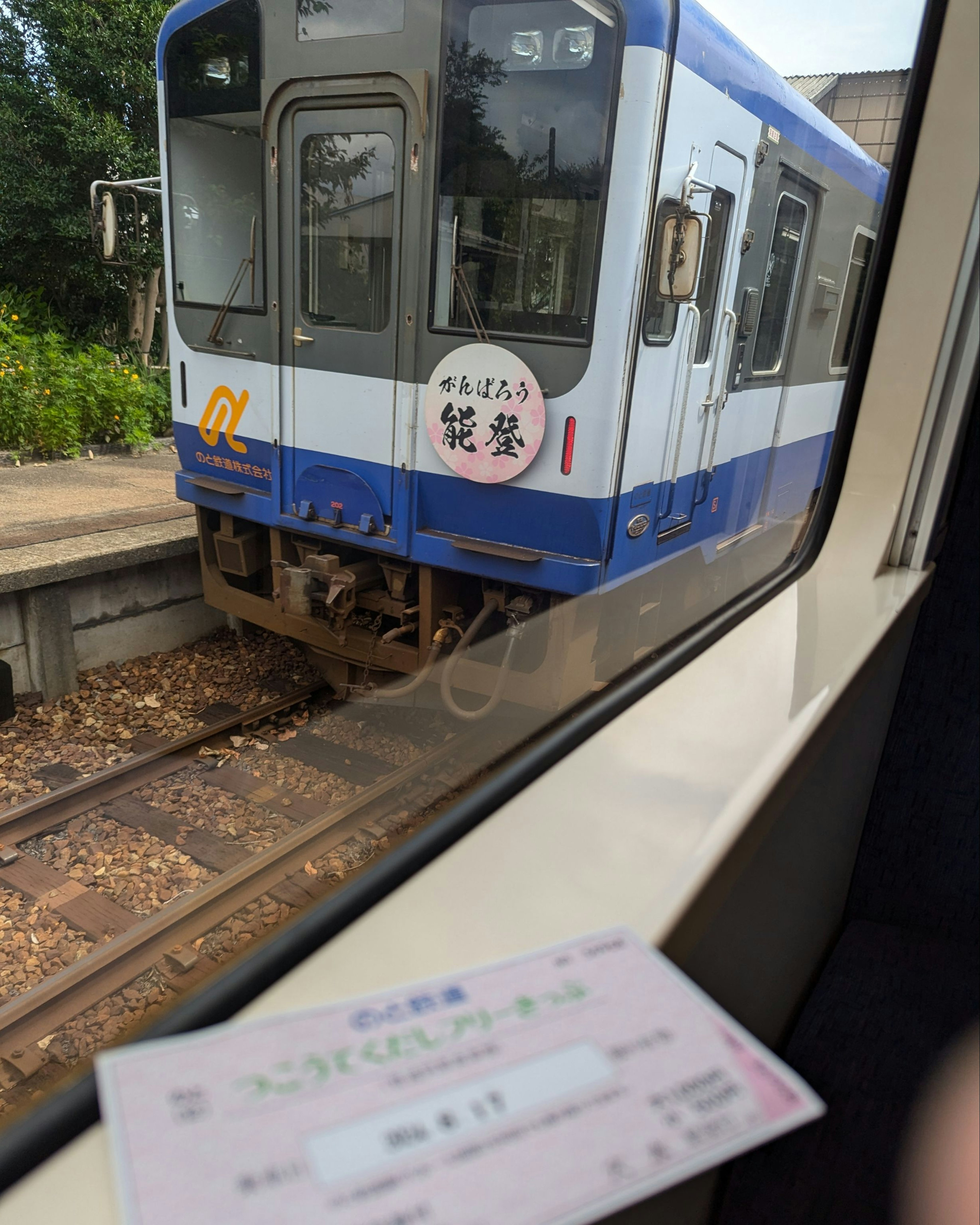 Vue depuis une fenêtre de train montrant un train et un billet