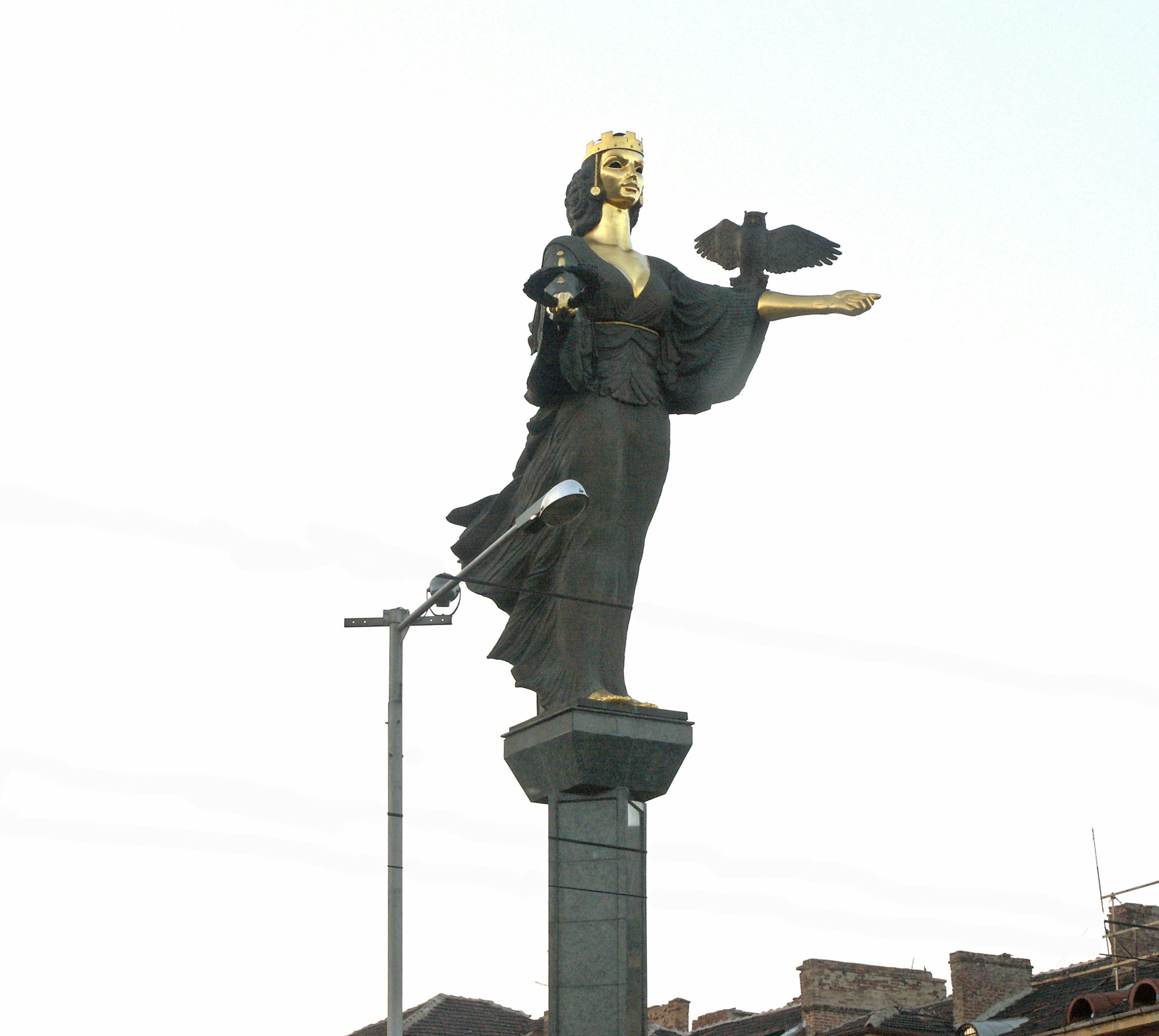 Una estatua de una mujer con rostro dorado se encuentra en la cima de una alta columna