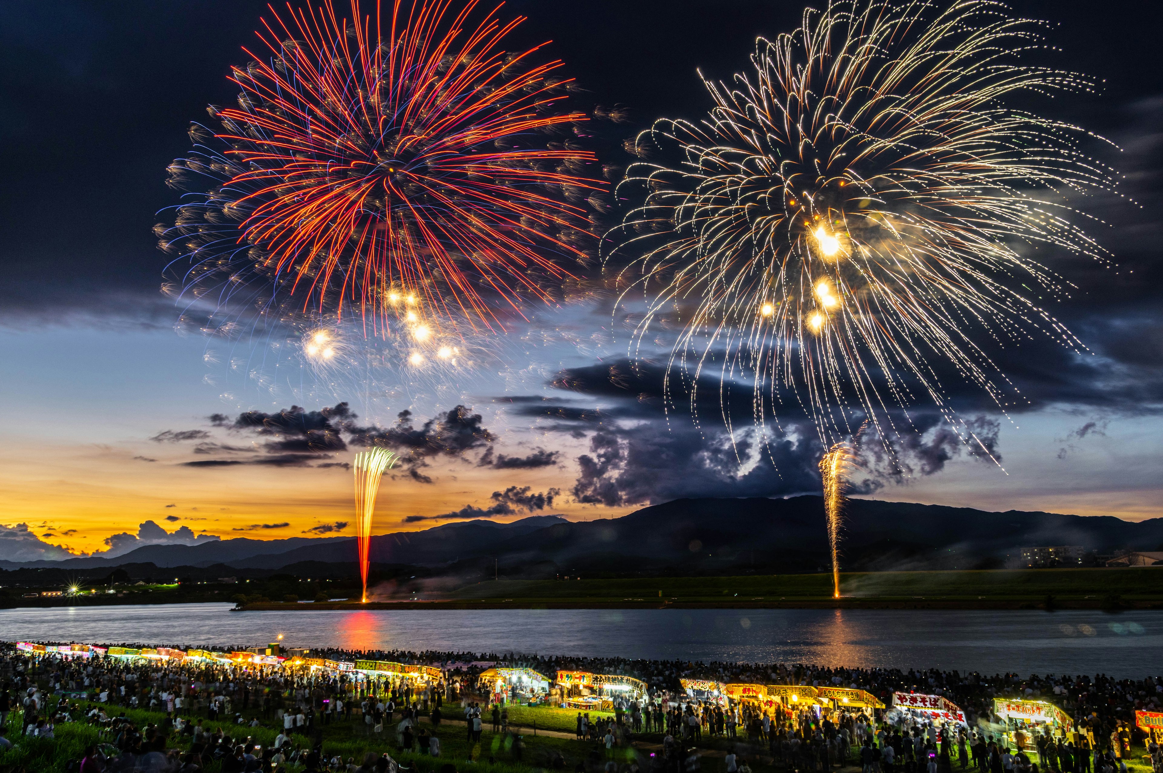 Hermosa escena de un espectáculo de fuegos artificiales al anochecer con espectadores