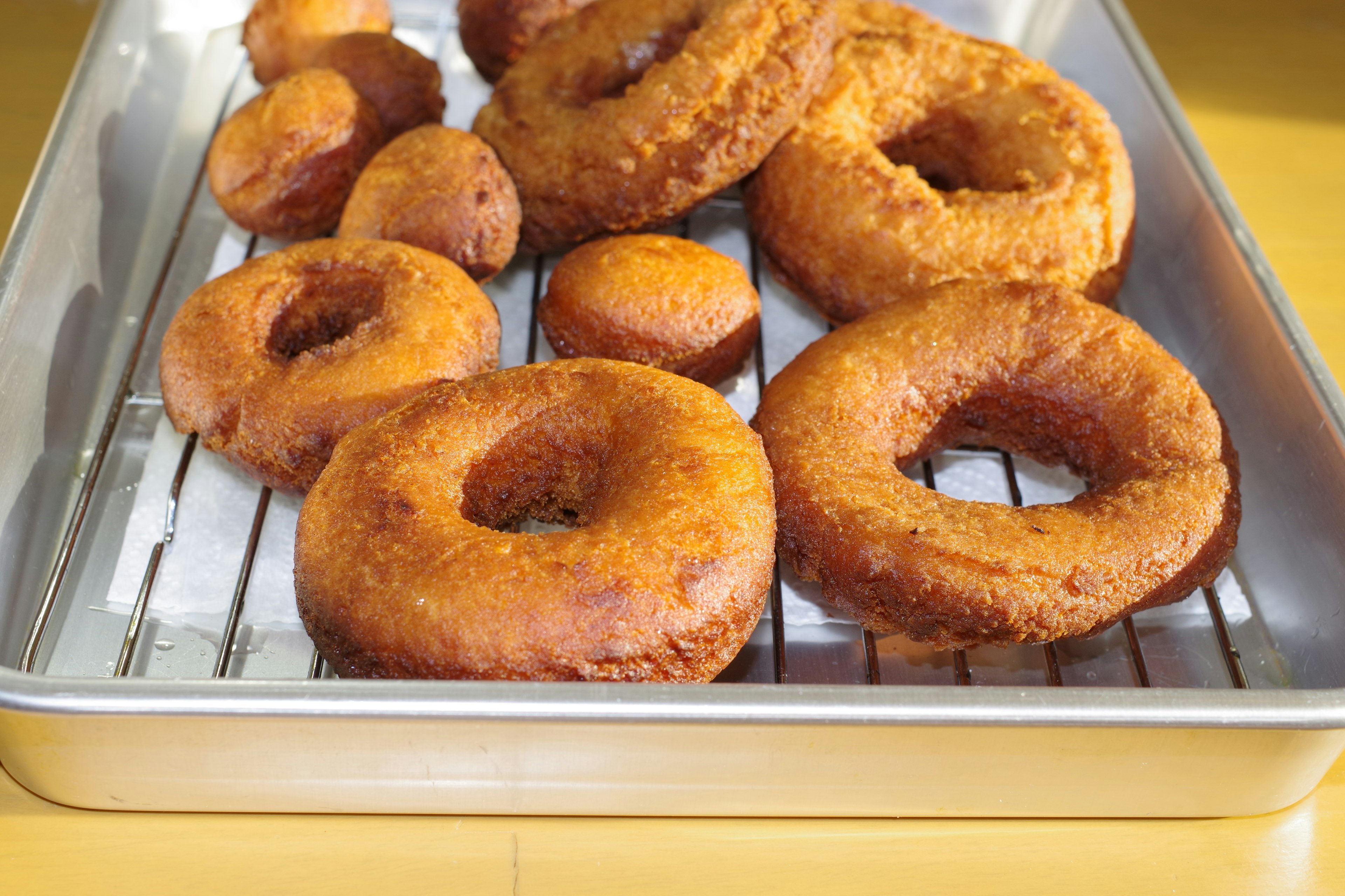 Freshly fried donuts arranged on a cooling rack