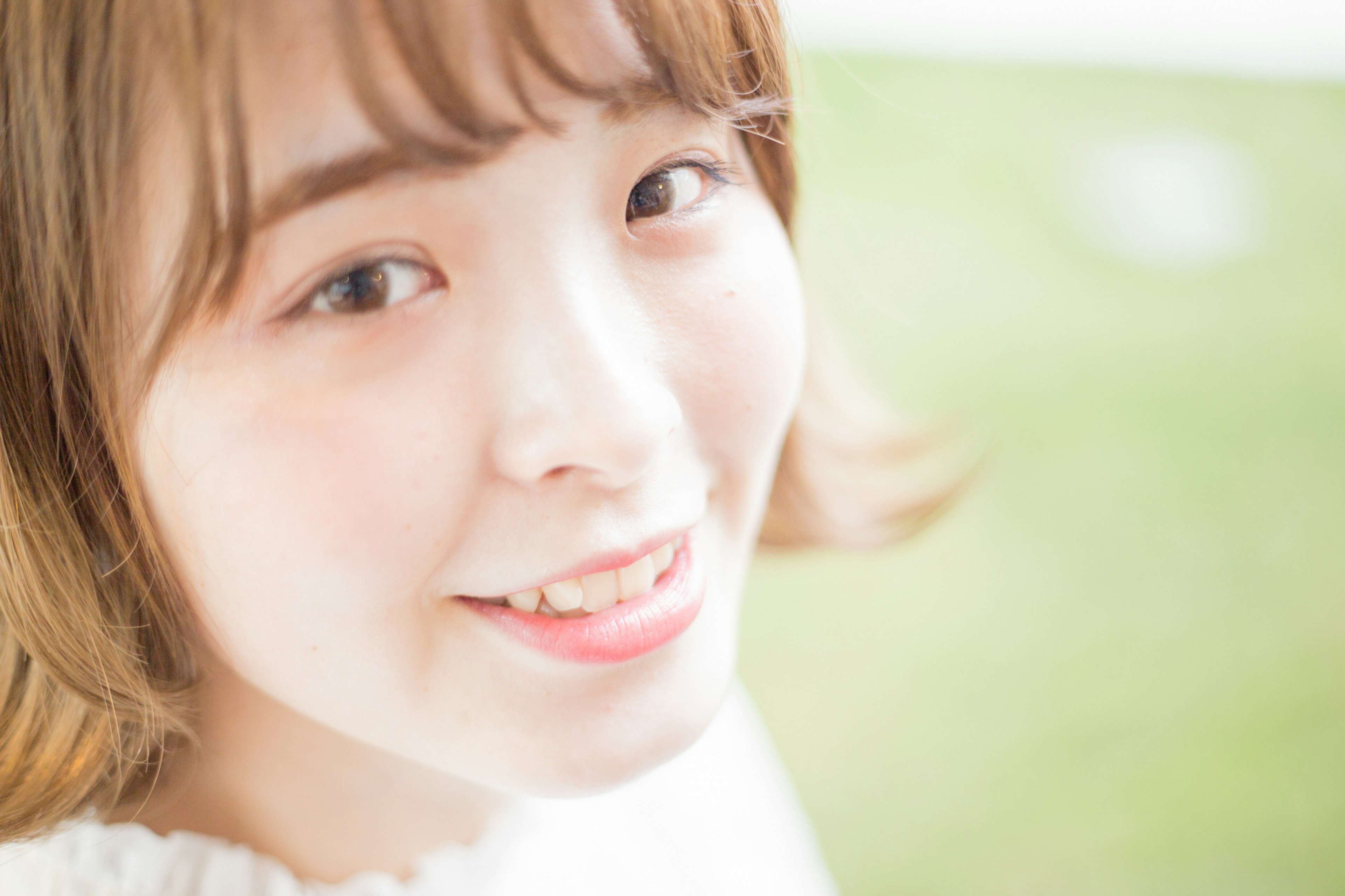 A smiling woman with a bright expression looking at the camera against a green background