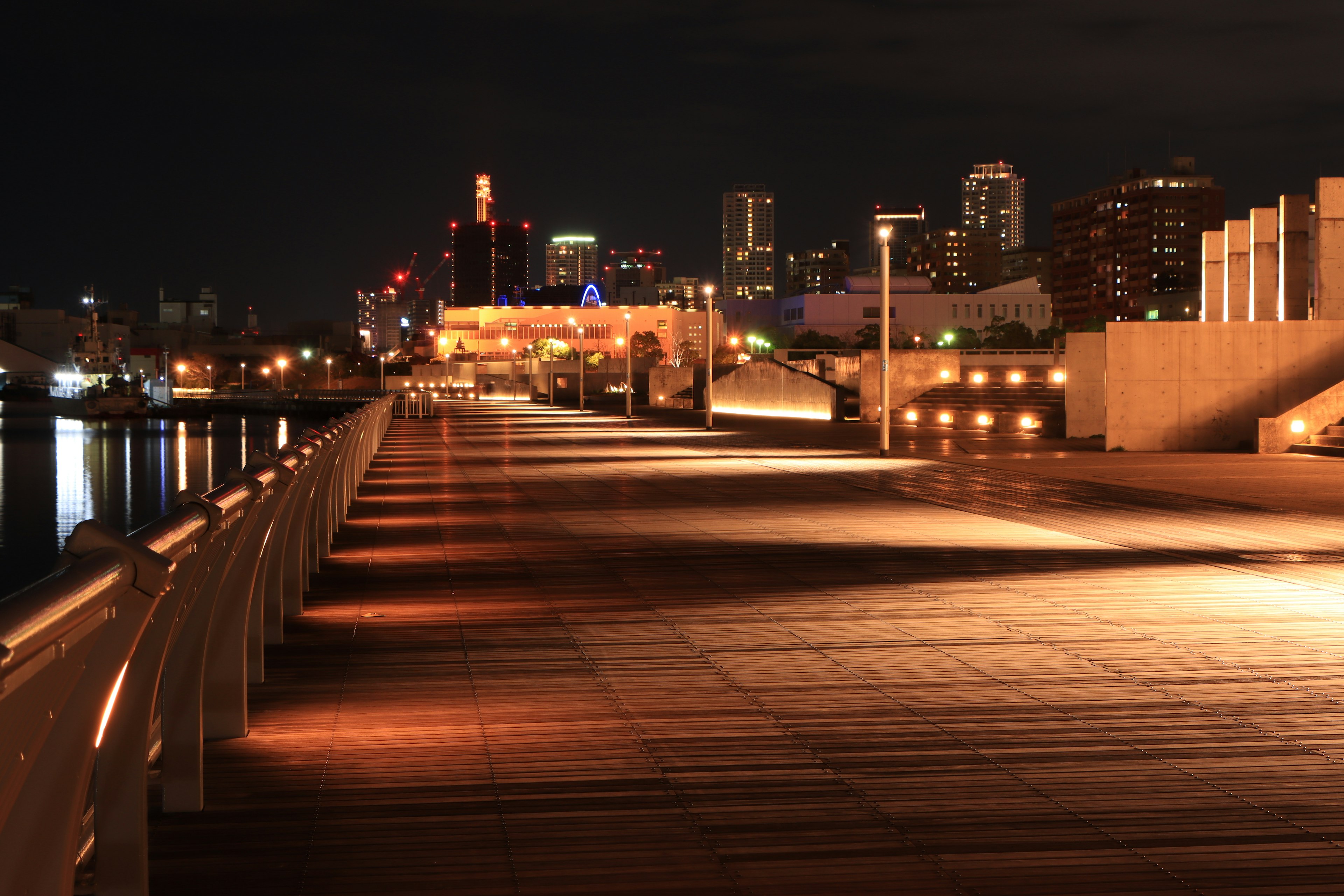 Vista nocturna de un muelle con el horizonte de la ciudad iluminado al fondo