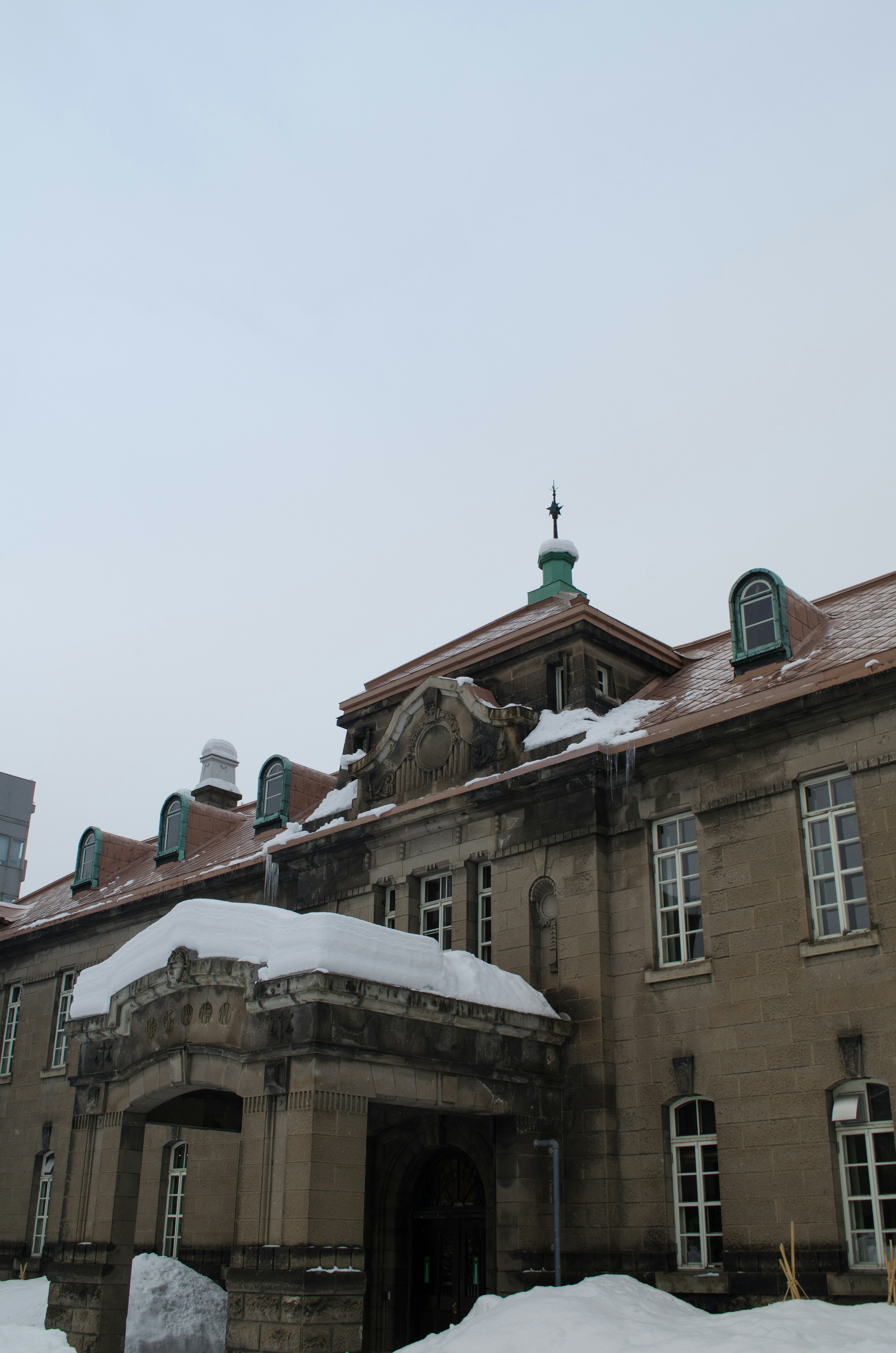 Extérieur d'un bâtiment historique recouvert de neige avec des fenêtres et un toit distinctifs