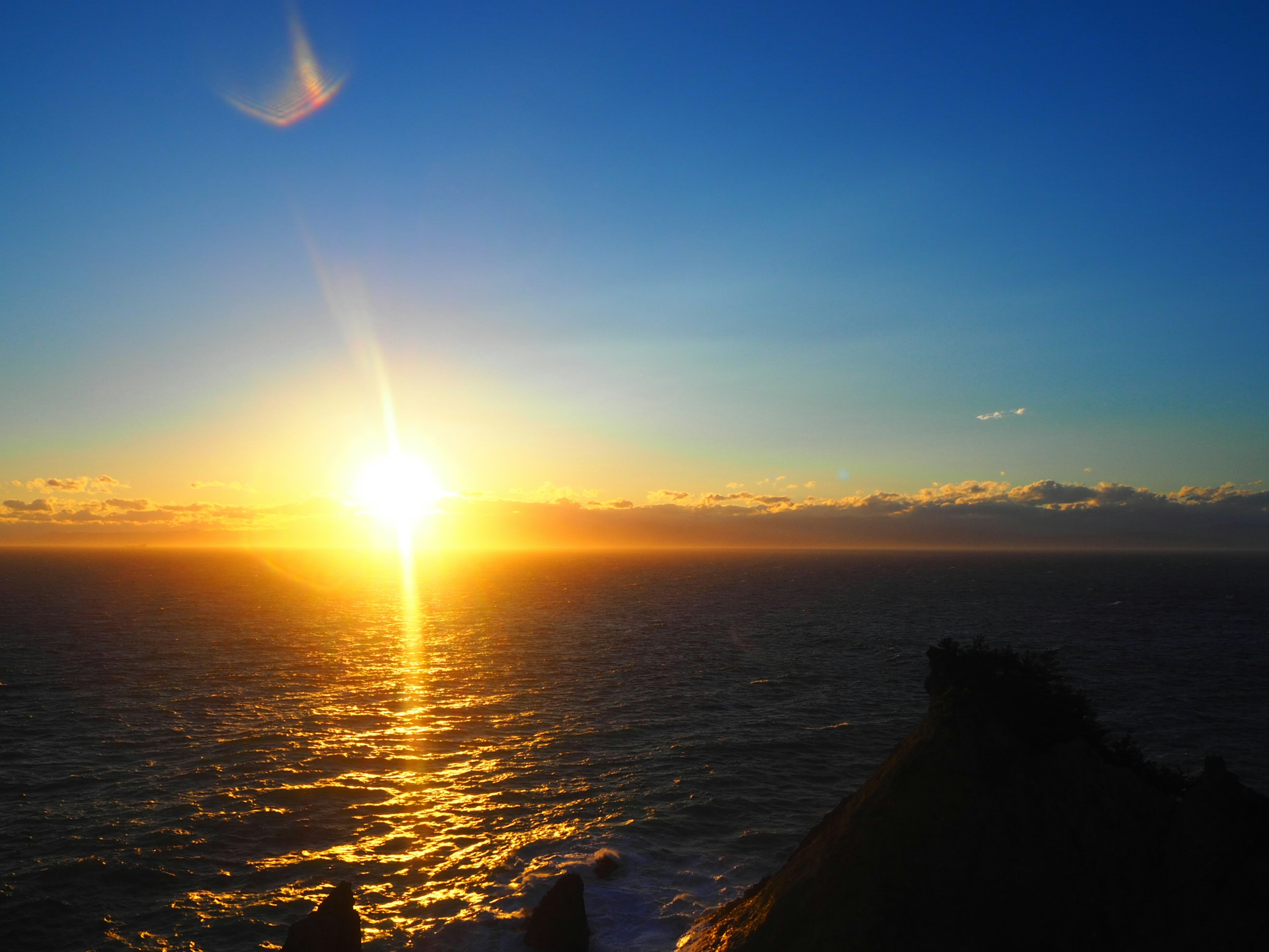 Beautiful landscape of a blue sky and orange sun setting over the ocean