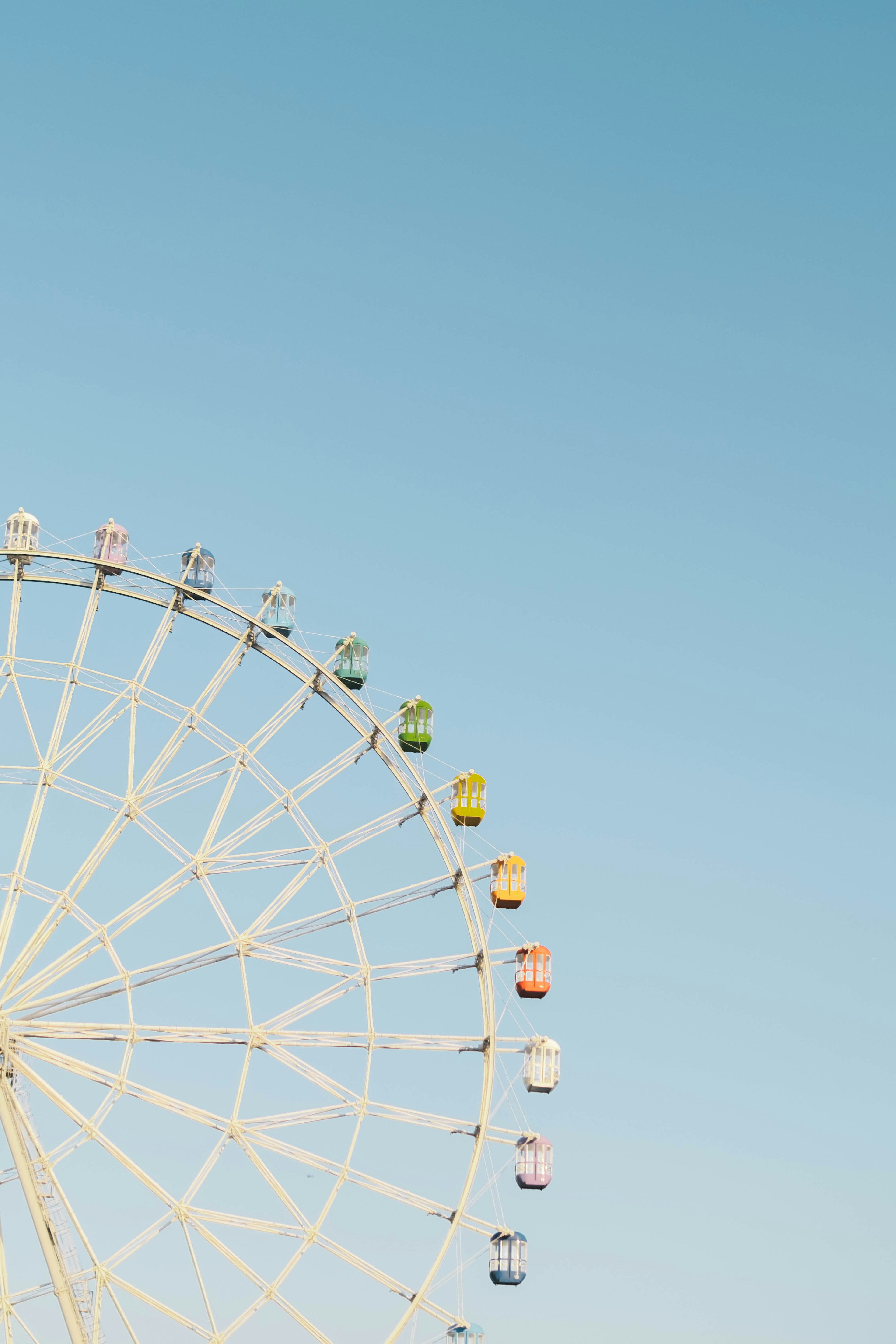 Vue partielle d'une grande roue sous un ciel bleu avec des capsules colorées