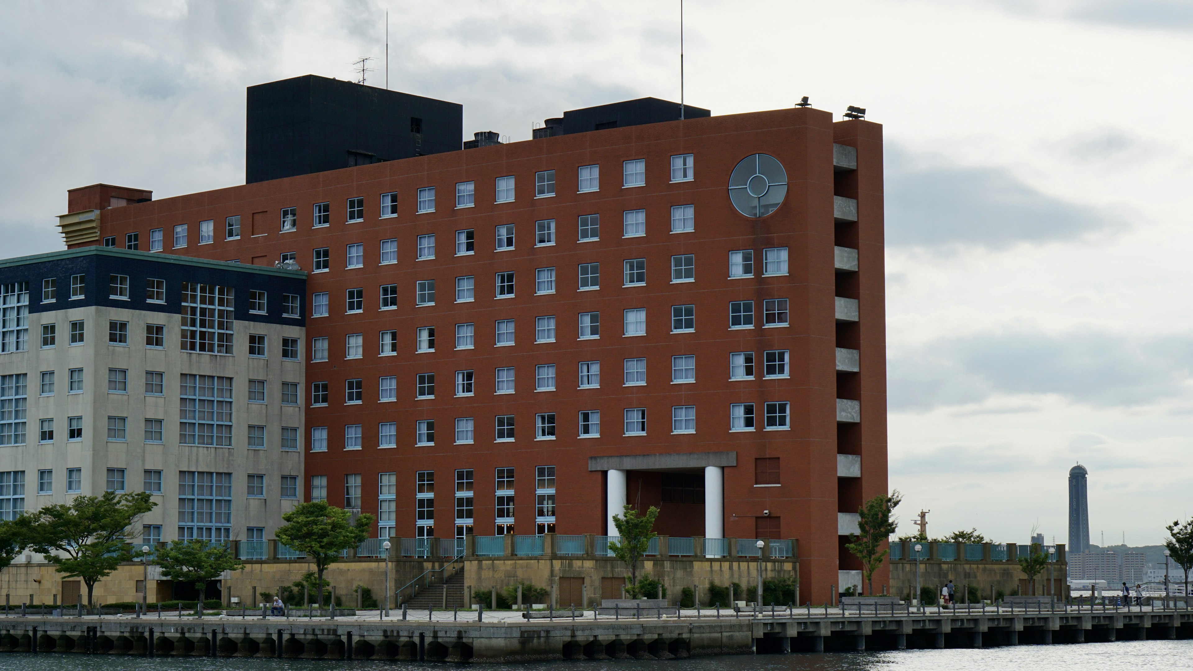 Bâtiment en brique rouge avec de grandes fenêtres et une horloge près de l'eau