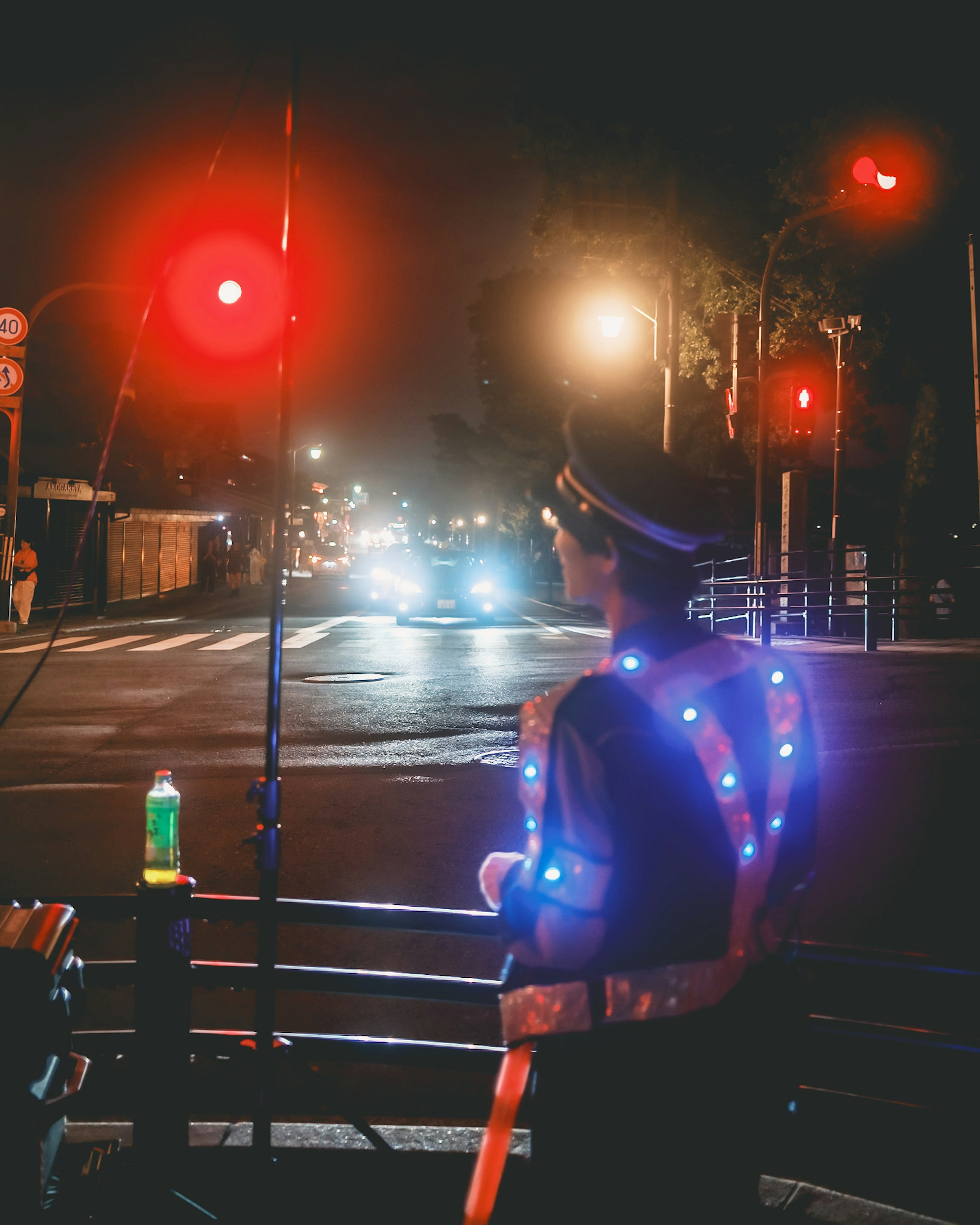 Poliziotto in piedi a un semaforo rosso di notte con un'uniforme illuminata