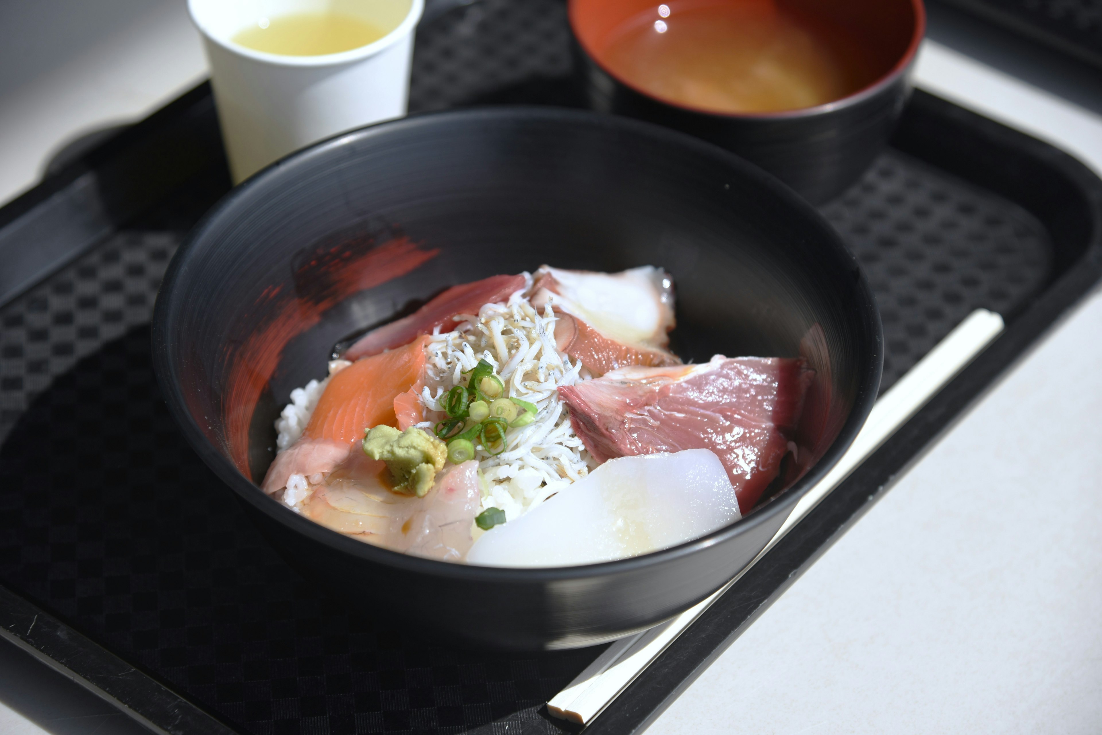 Bol de riz surmonté de sashimi frais et garni d'oignons verts