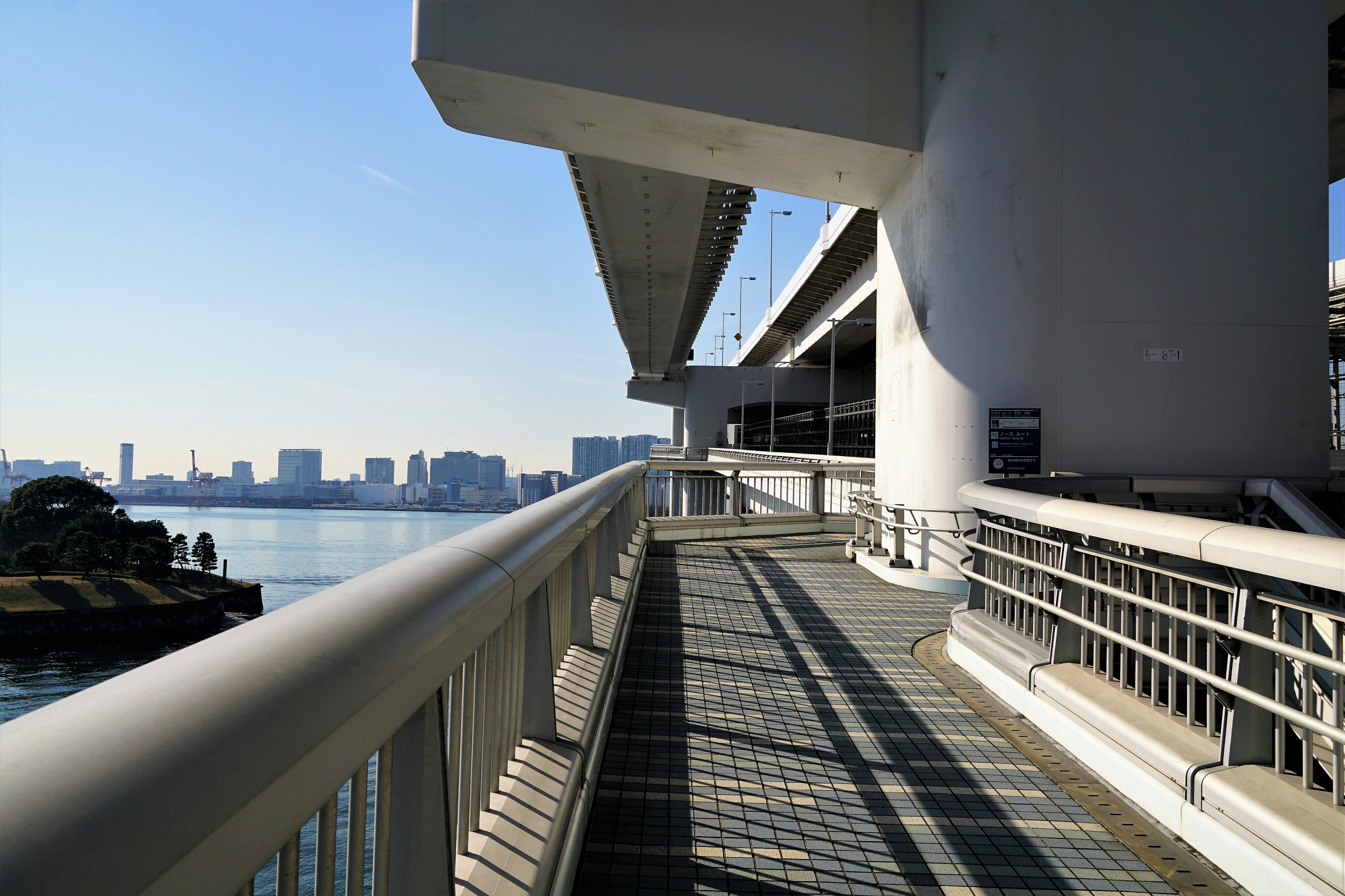 Moderner Fußweg einer Brücke mit Blick auf das Meer und die Skyline der Stadt