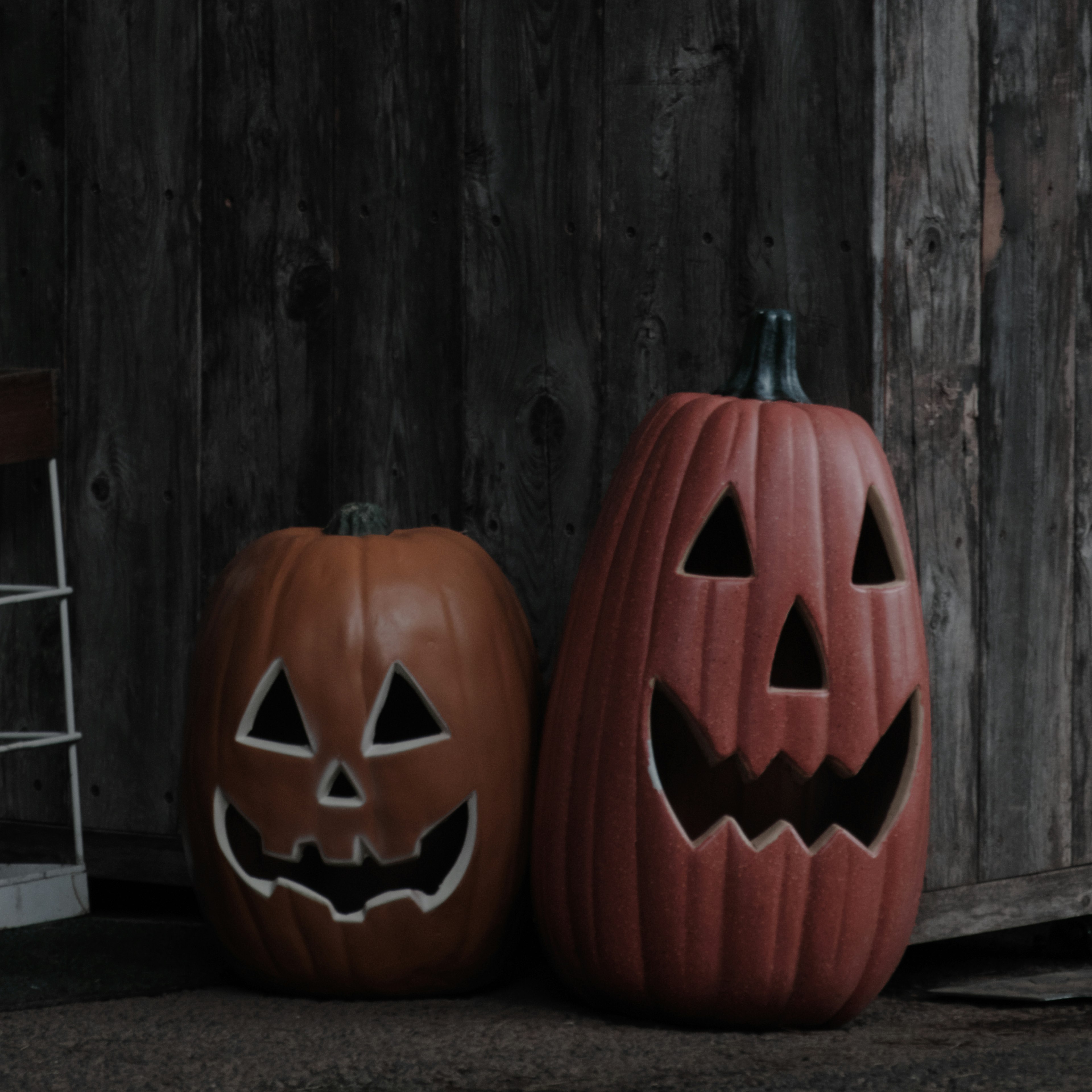 Two Halloween jack-o'-lanterns with carved faces on a rustic background