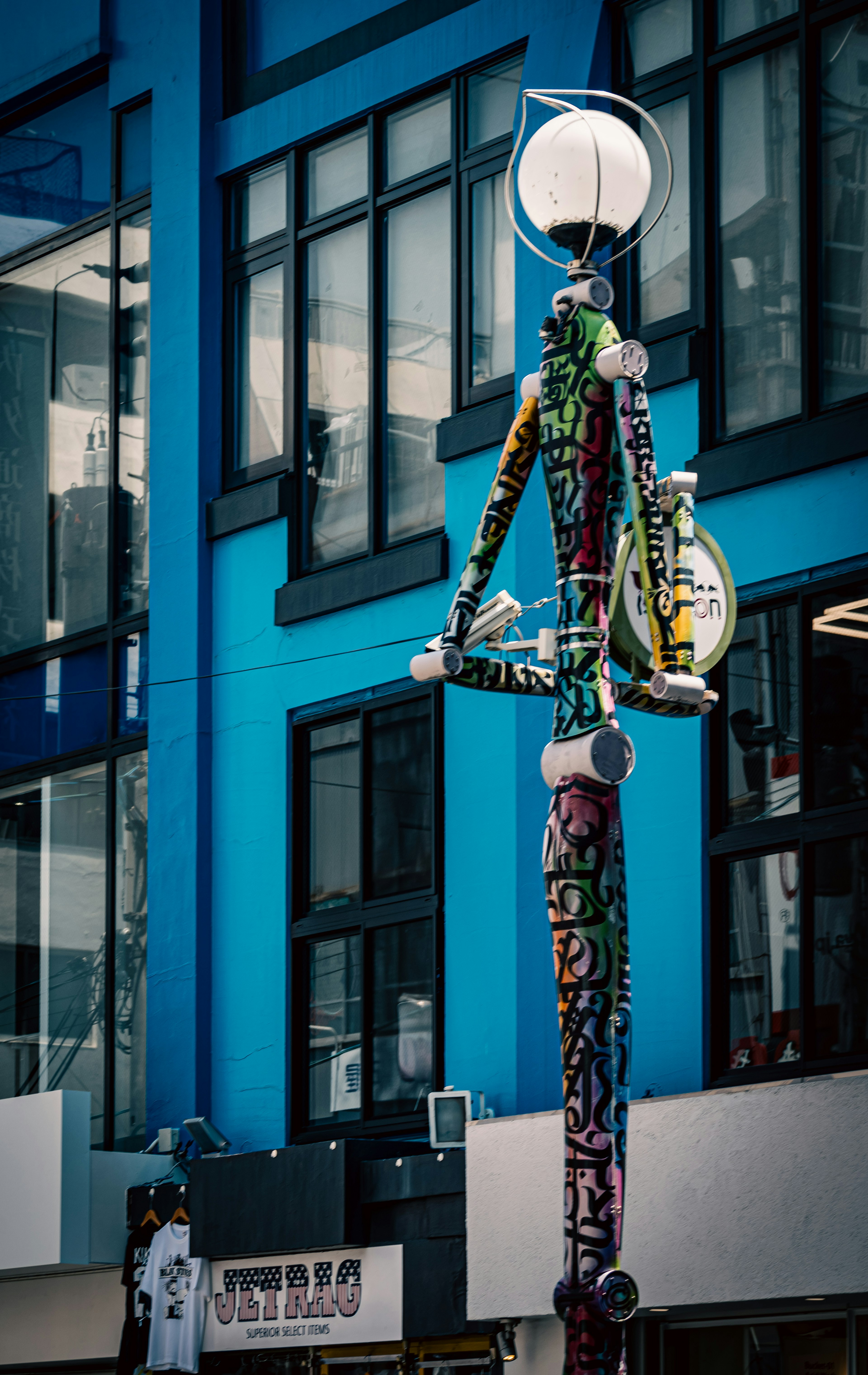 Buntes Straßenlampen-Kunstwerk vor einer blauen Wand