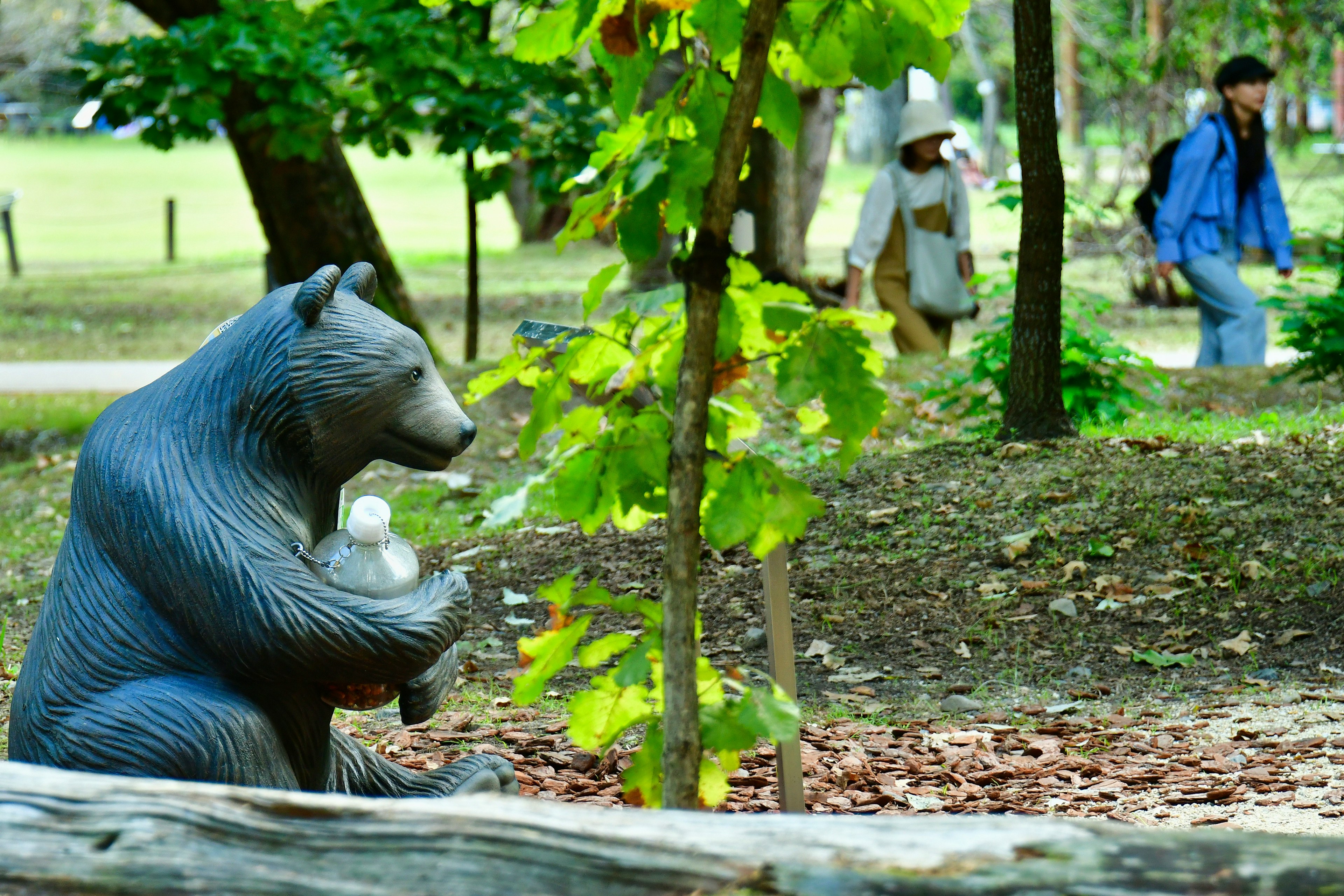 公園の中にいるクマの彫刻と散歩する人々