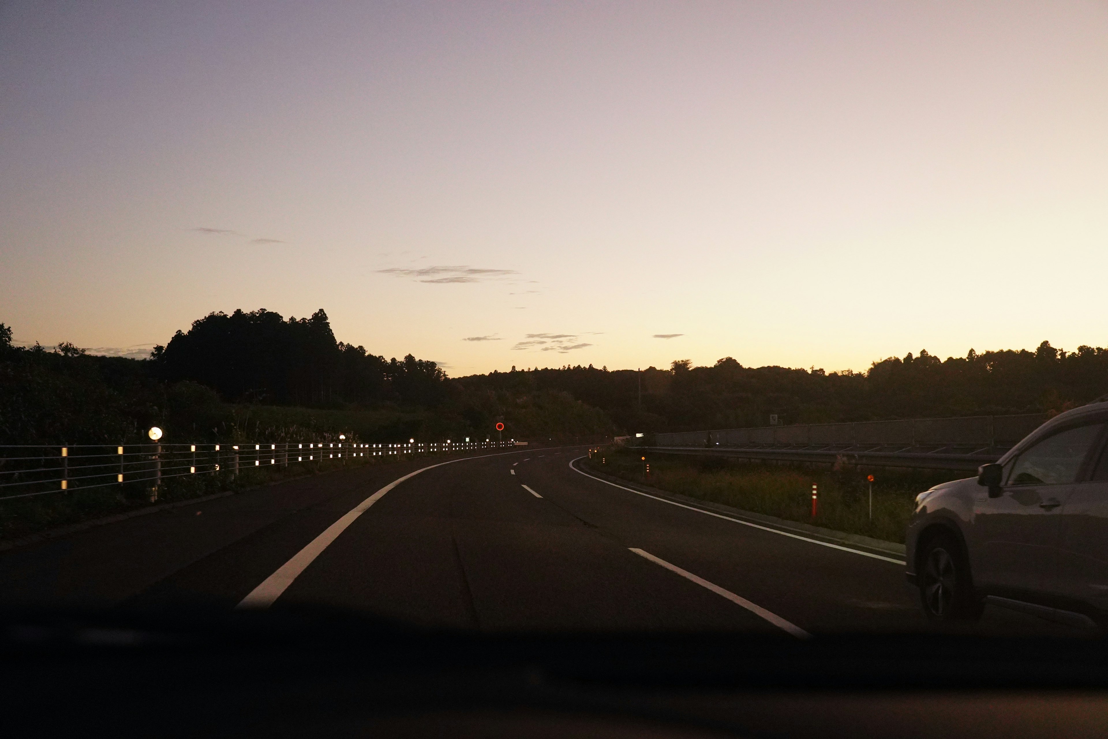 Vista crepuscolare di un'autostrada con un'auto in movimento