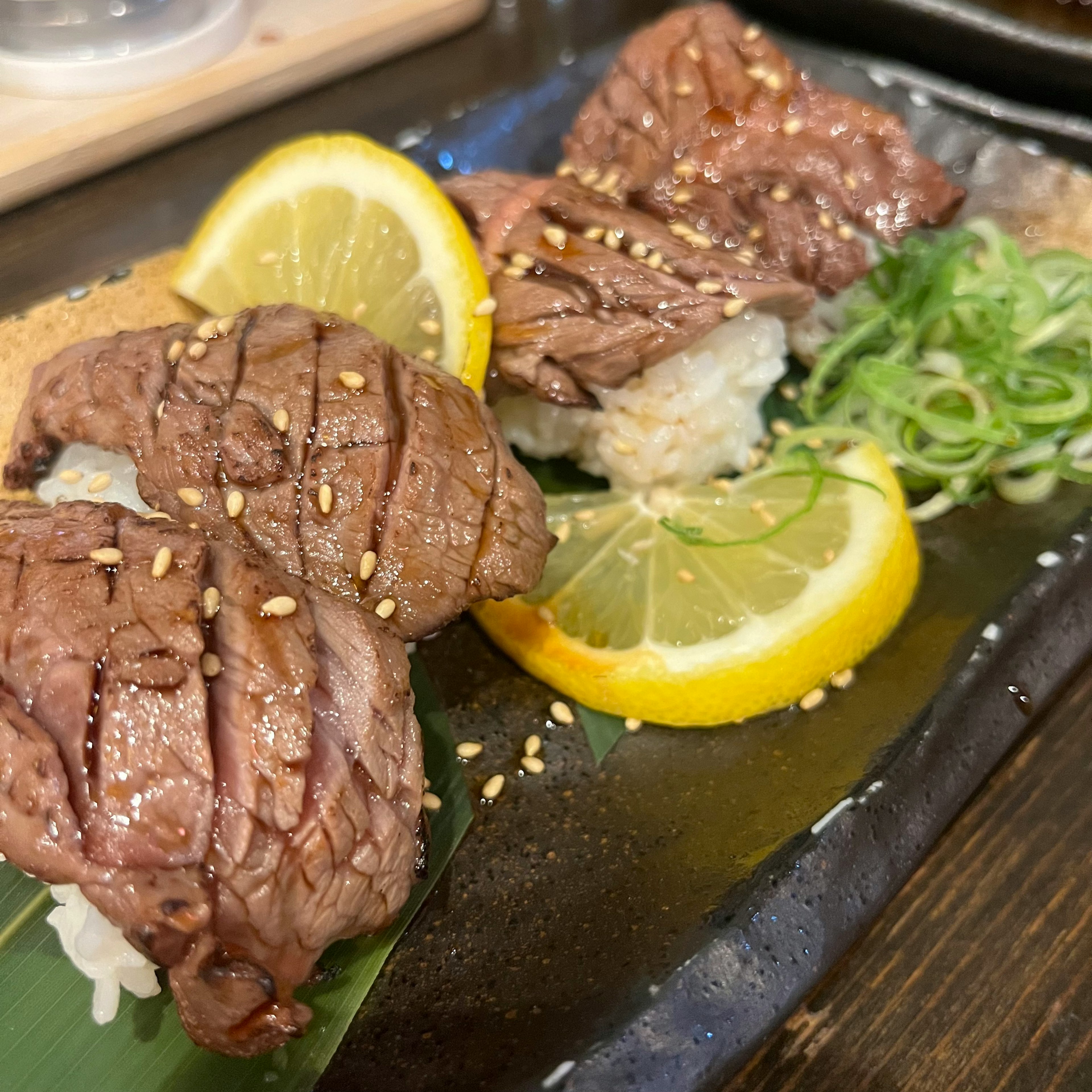 レモンとネギと一緒に盛り付けられた肉の寿司