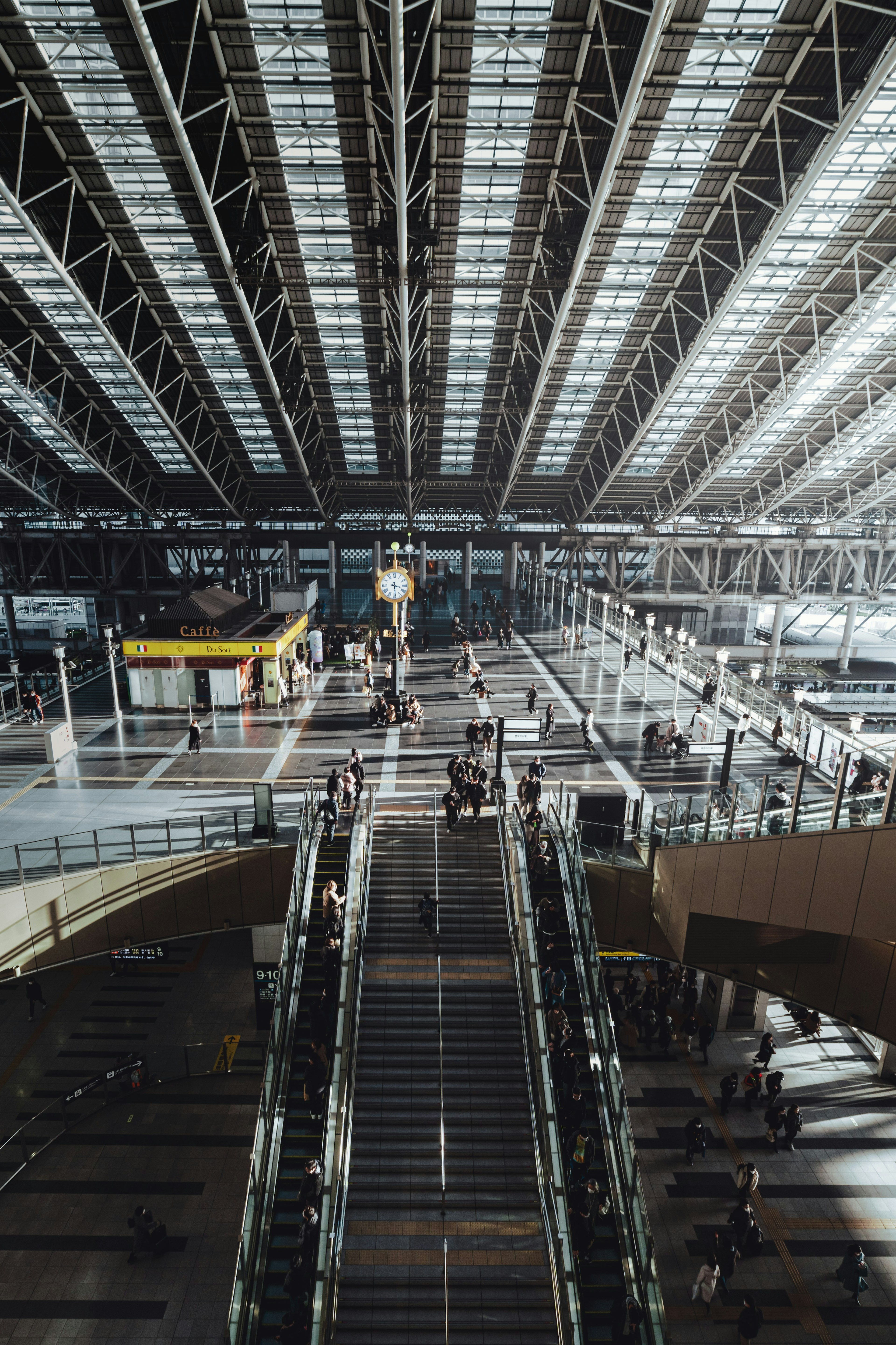 Spacious interior of a train station, bright roof, stairs, passengers