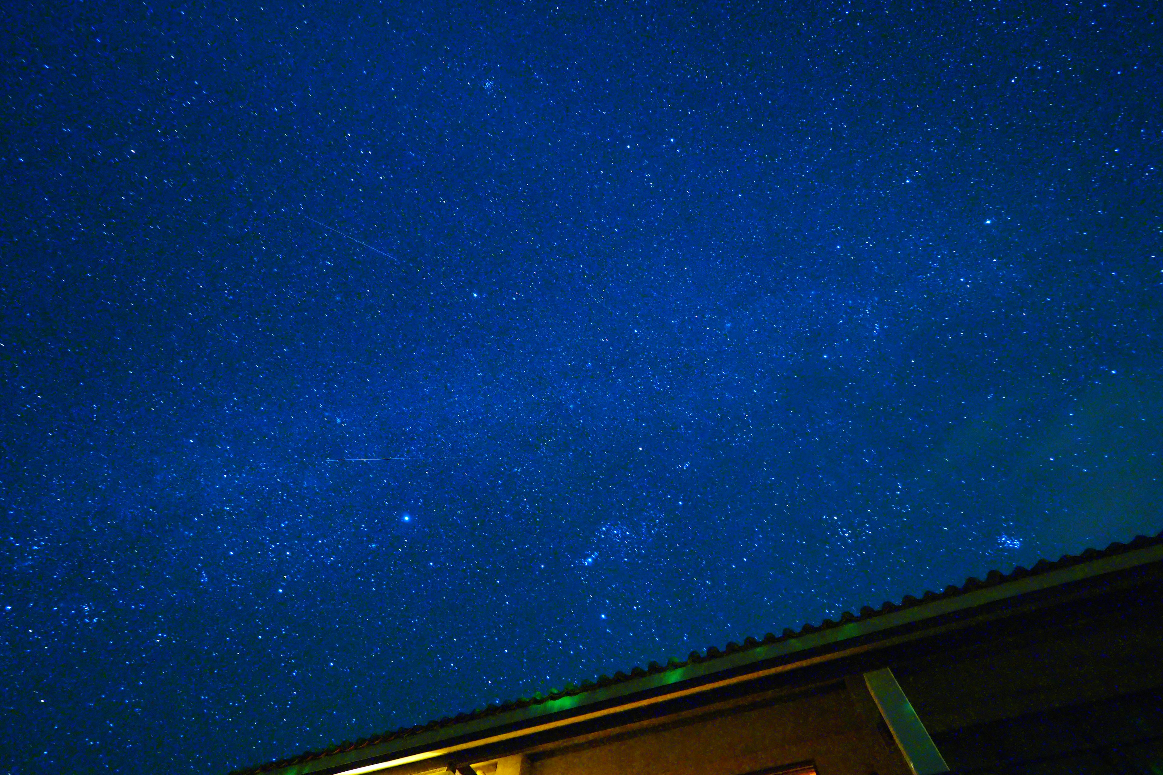 Cielo notturno blu stellato con un accenno a un tetto