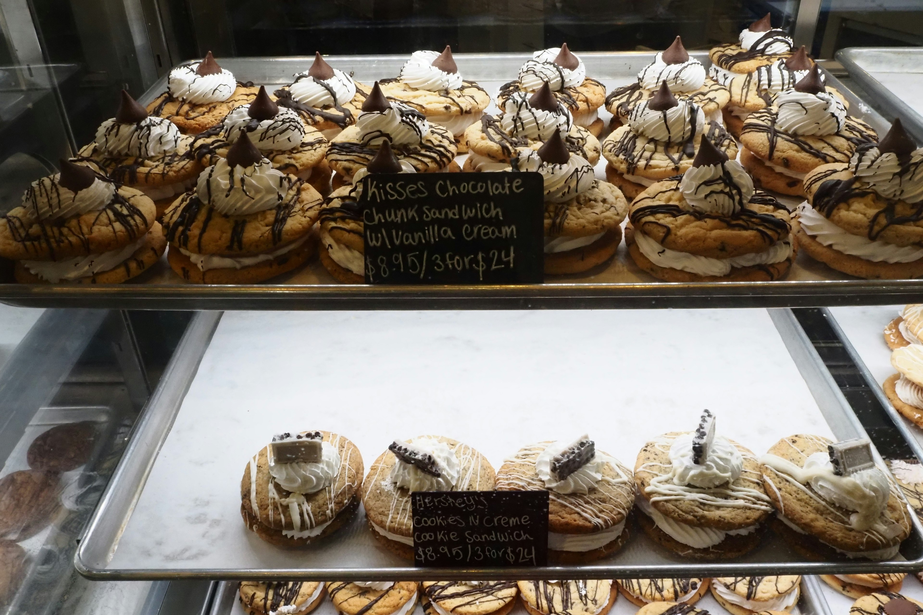 Display case filled with various delicious desserts topped with cream and chocolate