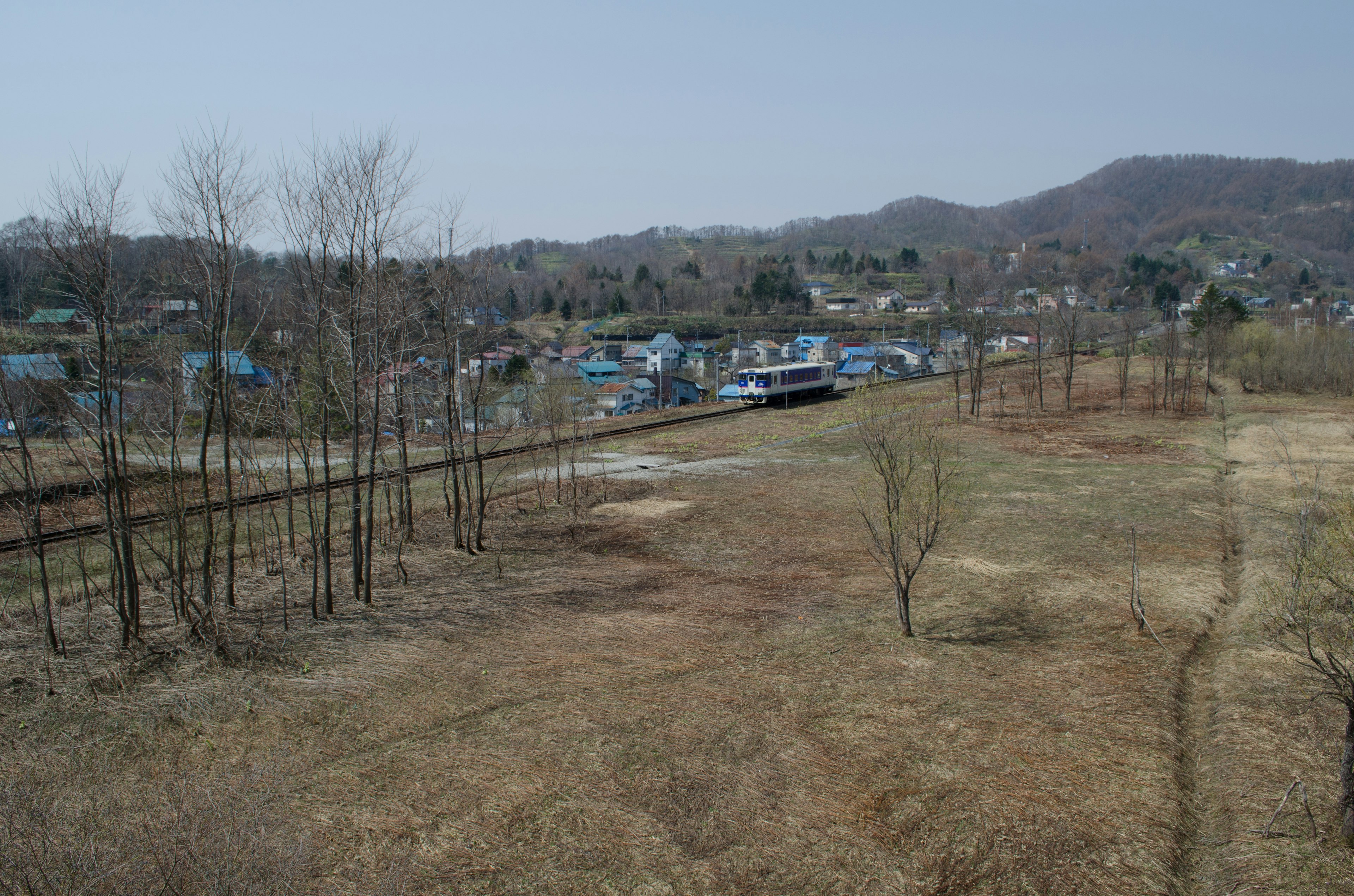 Landschaft mit blauen Häusern und sichtbaren Bahngleisen