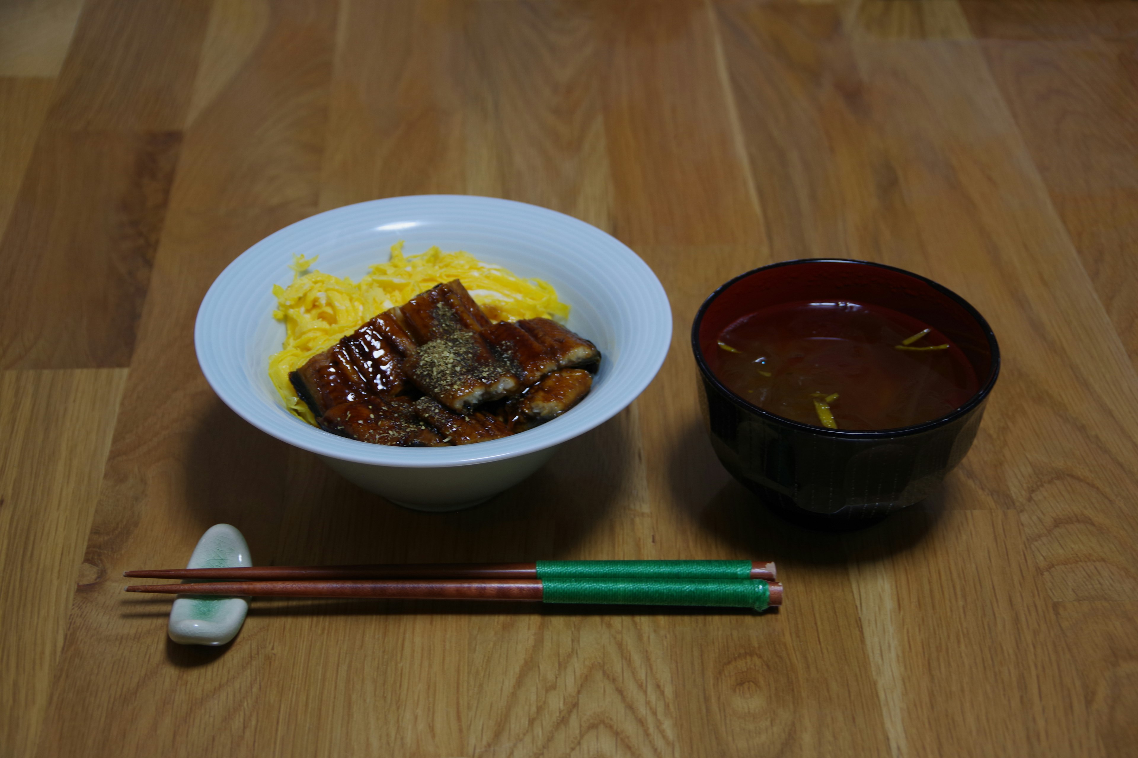 A bowl of rice topped with eel and a side of miso soup