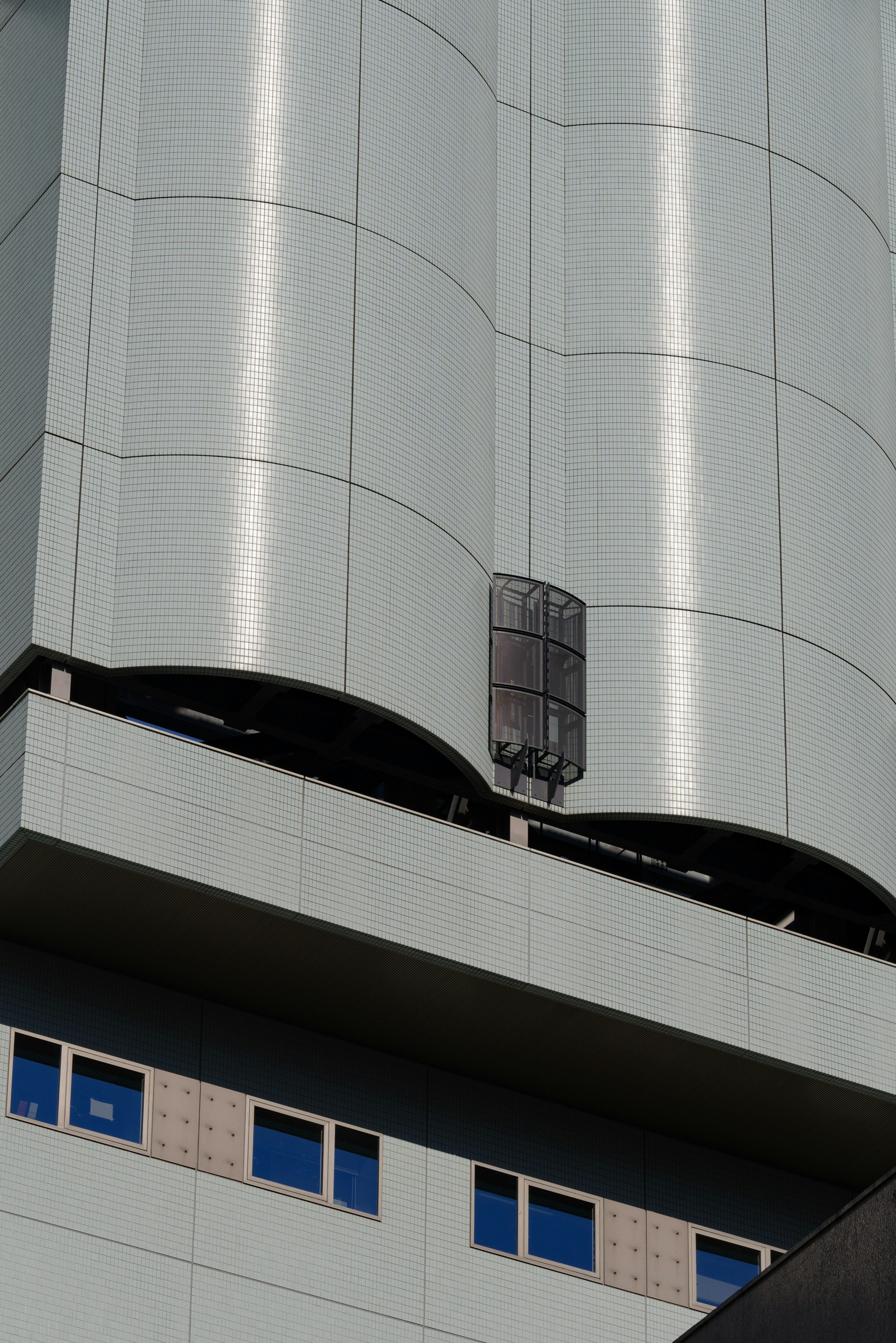 Part of a modern building featuring a metallic exterior and blue windows