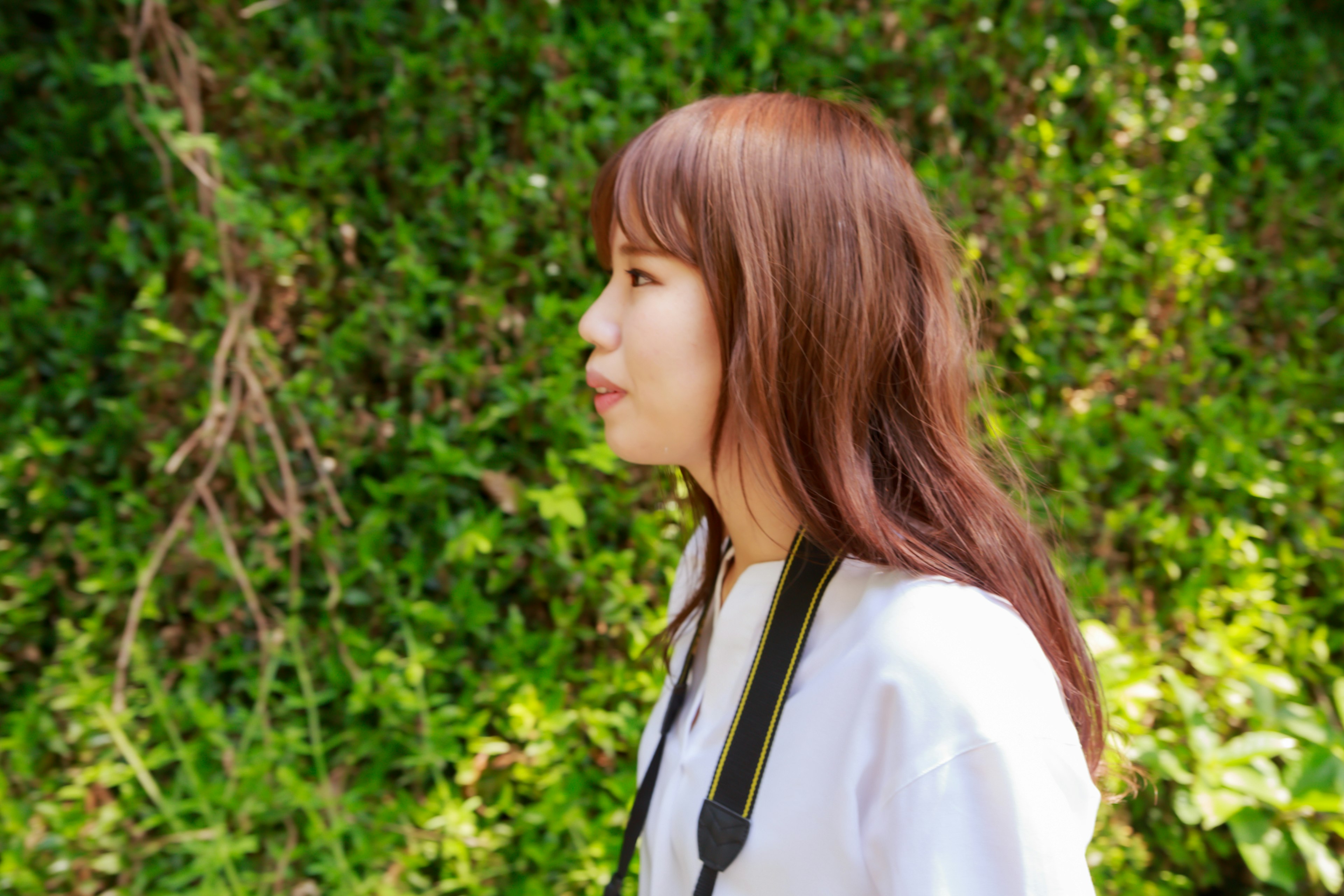 Profil d'une femme devant un arrière-plan vert avec des cheveux bruns et un appareil photo